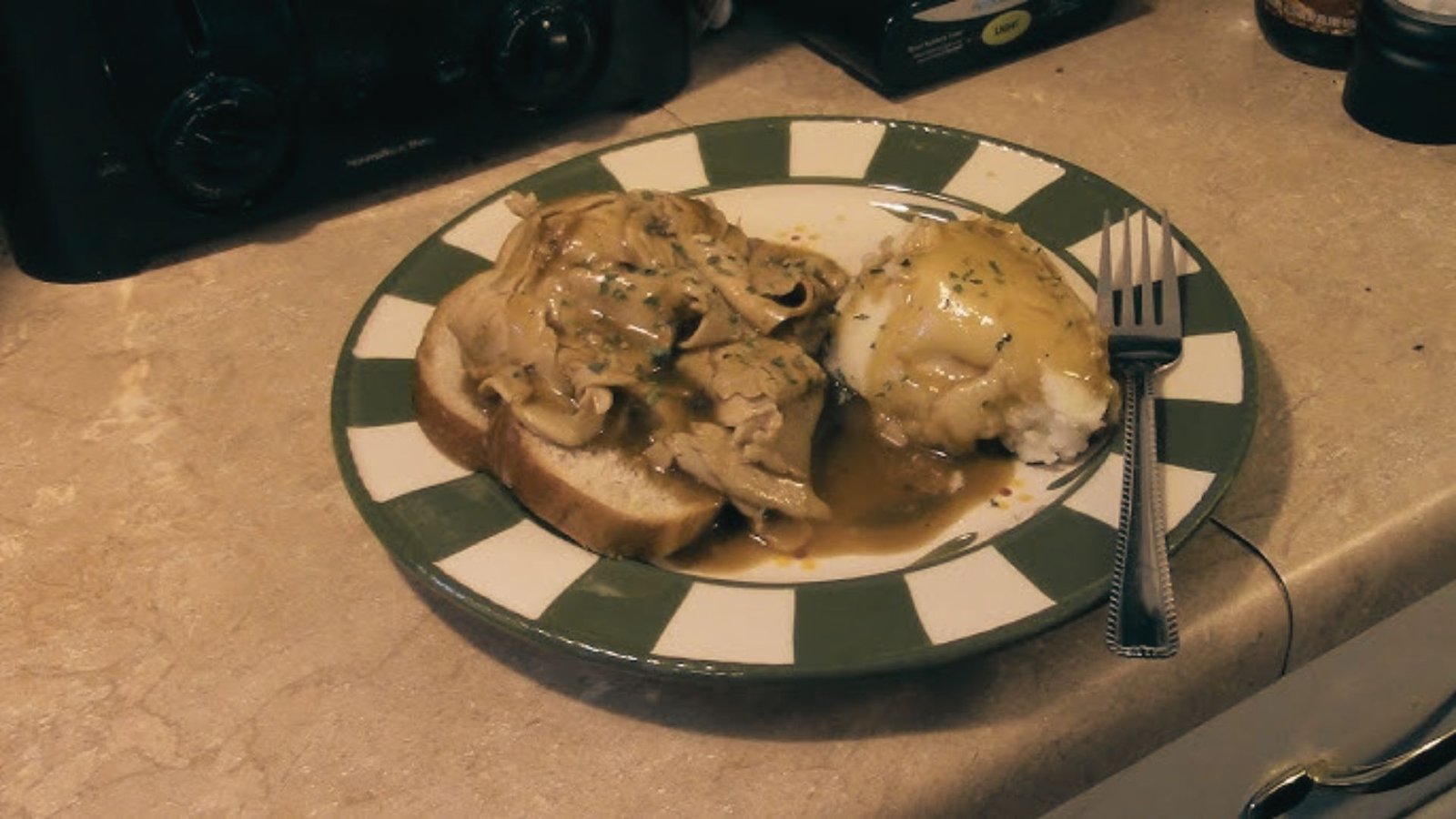 A plate featuring sliced turkey topped with rich gravy, part of an Easy Leftover Turkey Manhattan recipe.