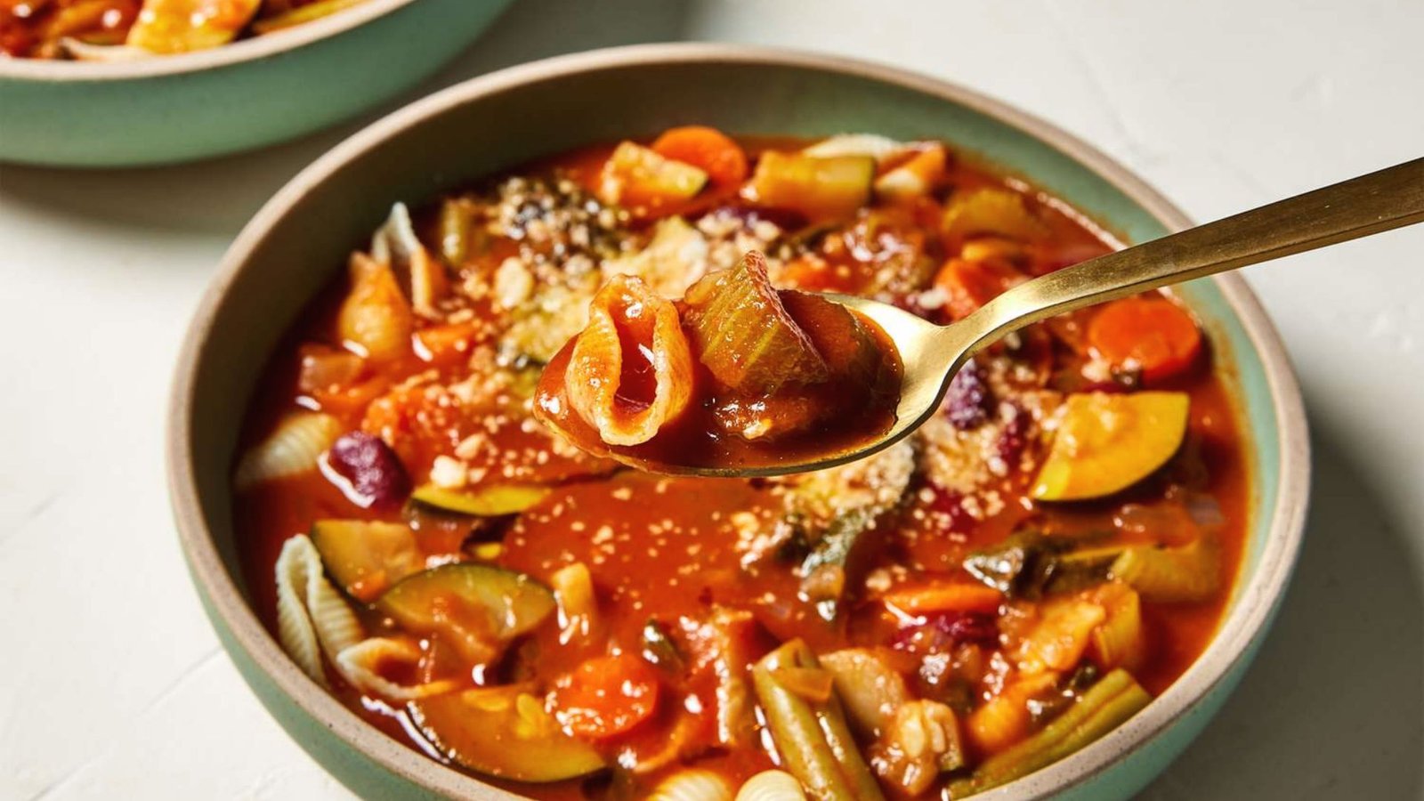 A bowl of hot Beef Minestrone Soup with a spoon, ready to be served after final simmering and tasting.