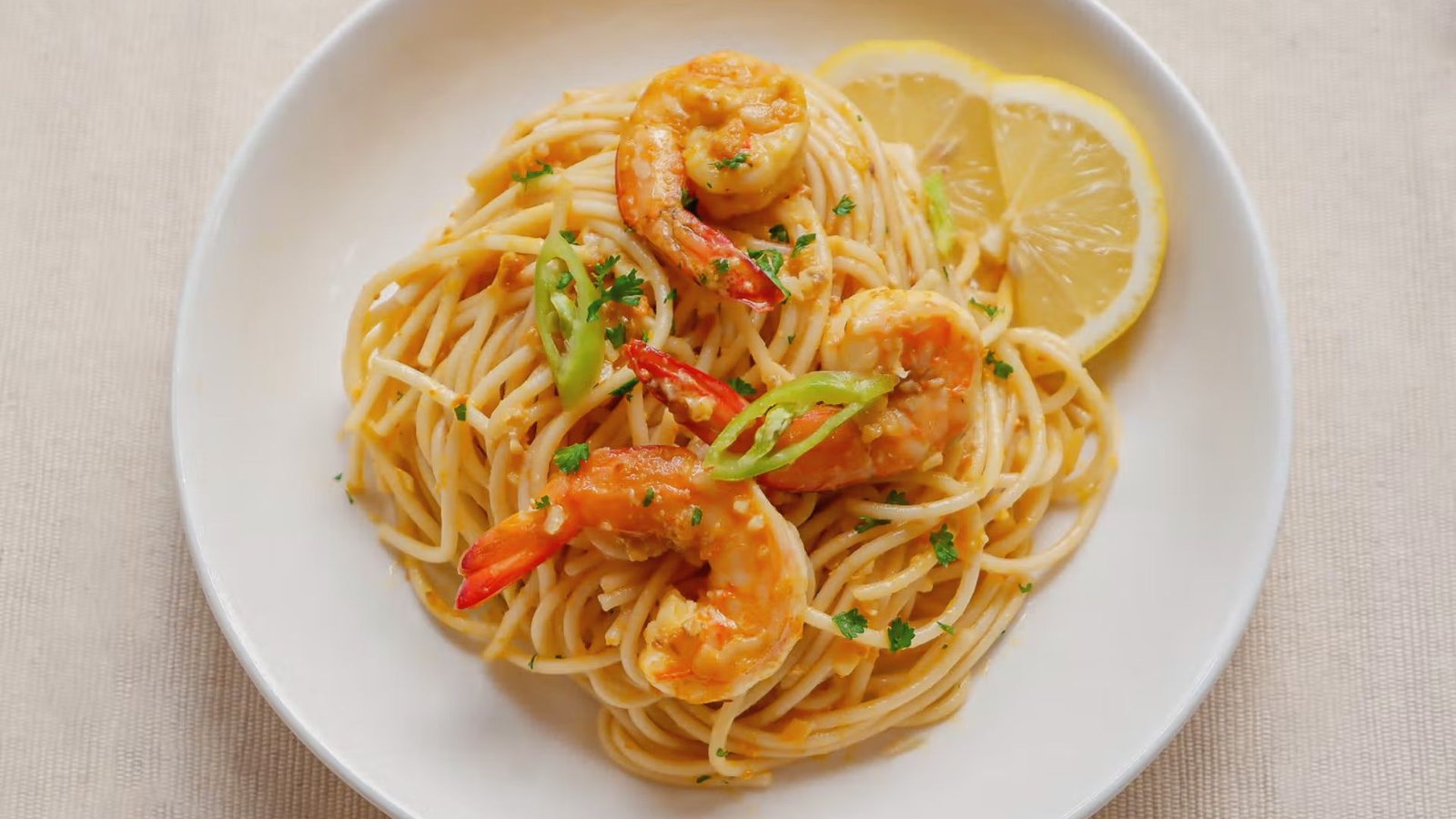 A plate of spaghetti topped with shrimp and served with lemon wedges, ideal for pairing with crab and shrimp pasta.