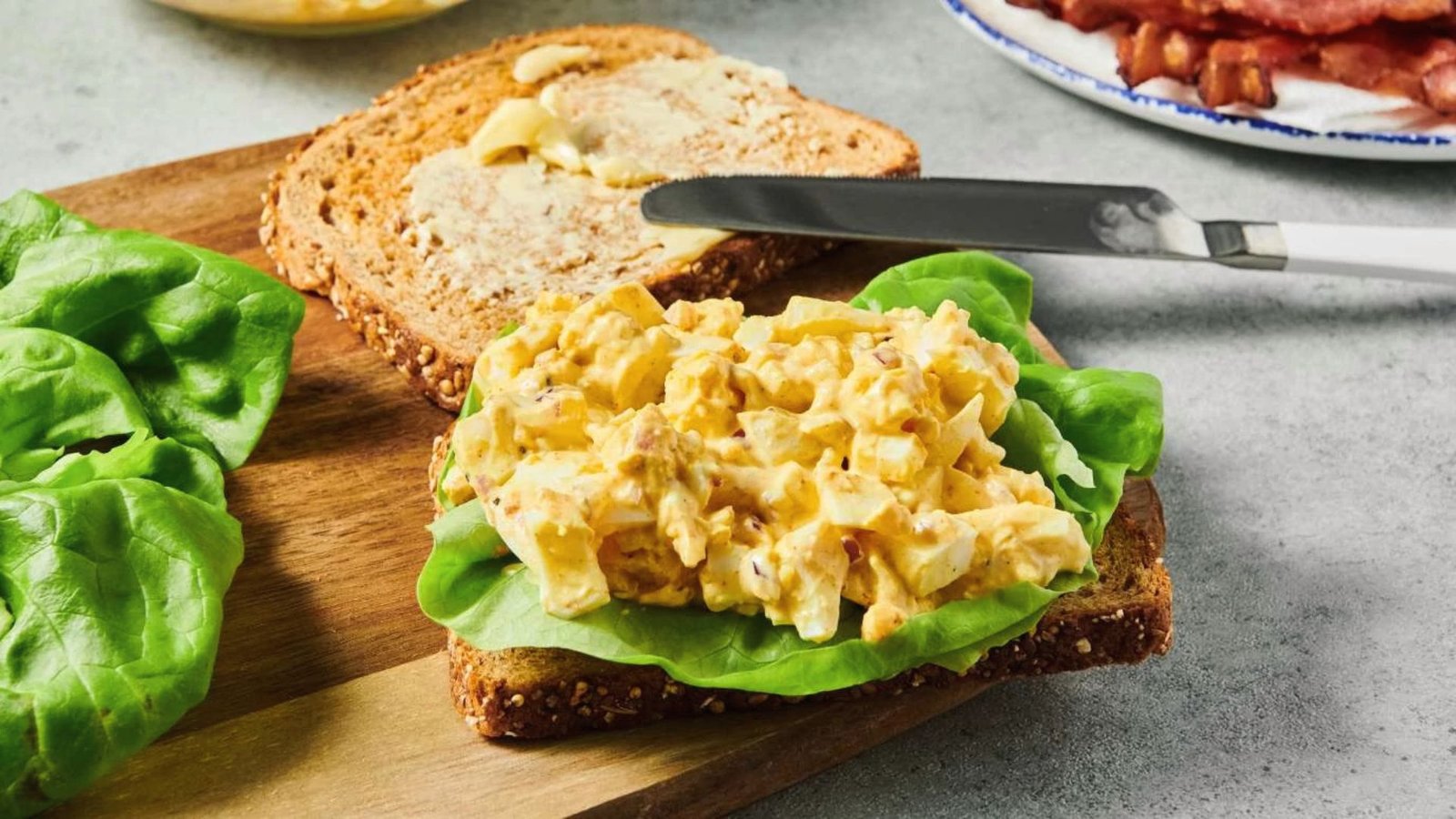 A sandwich with egg pickle salad and lettuce on a wooden cutting board, showcasing a quick serving idea with pickles.