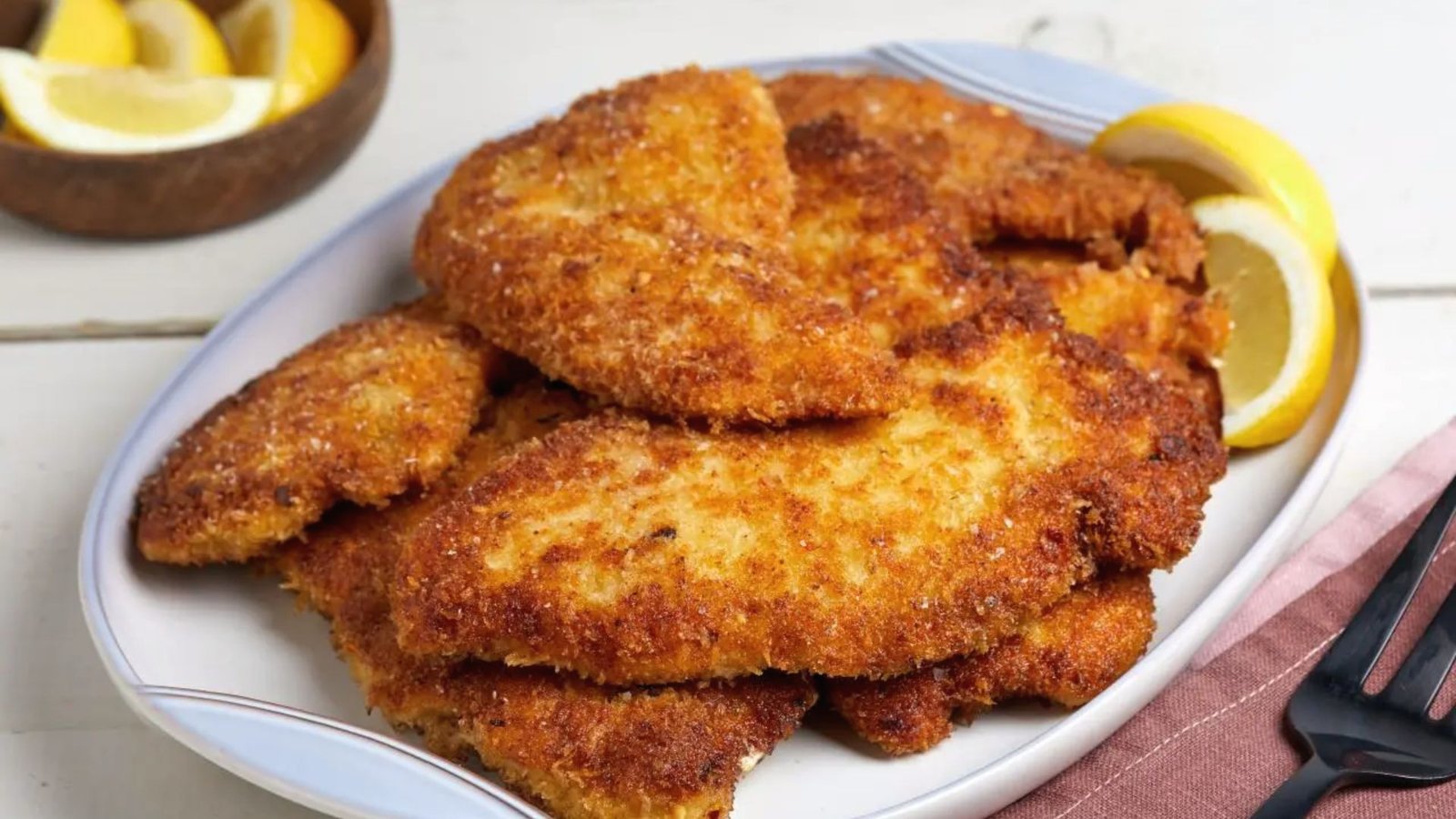 Chicken cutlets served on a plate with fresh lemon wedges for added flavor.