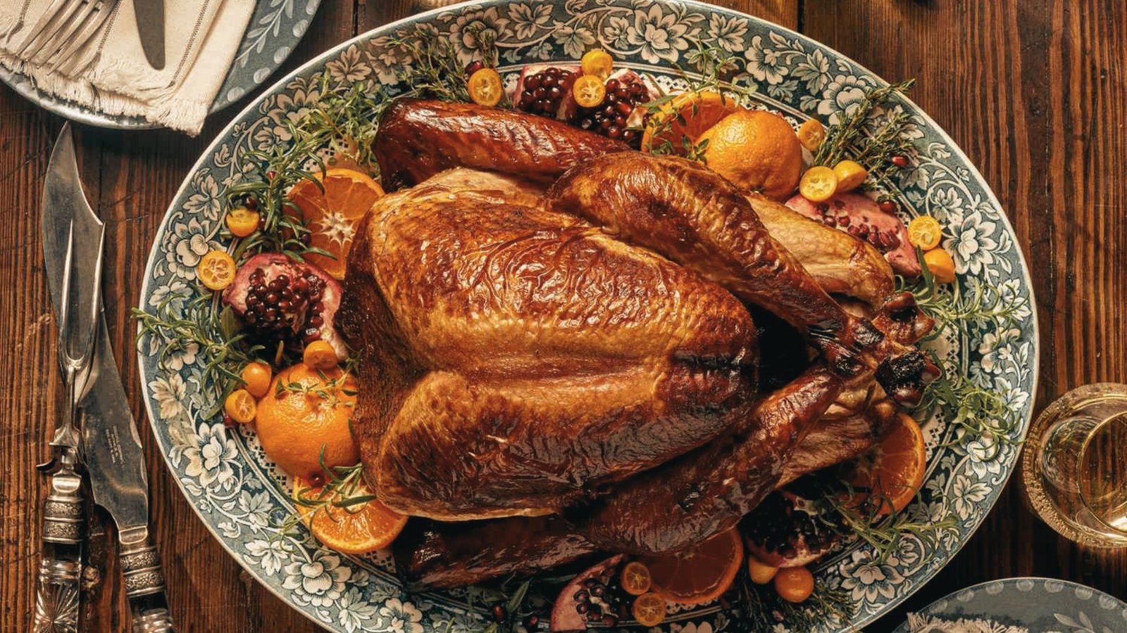 A beautifully roasted turkey on a platter, garnished with Lemon and accompanied by an array of delicious foods.