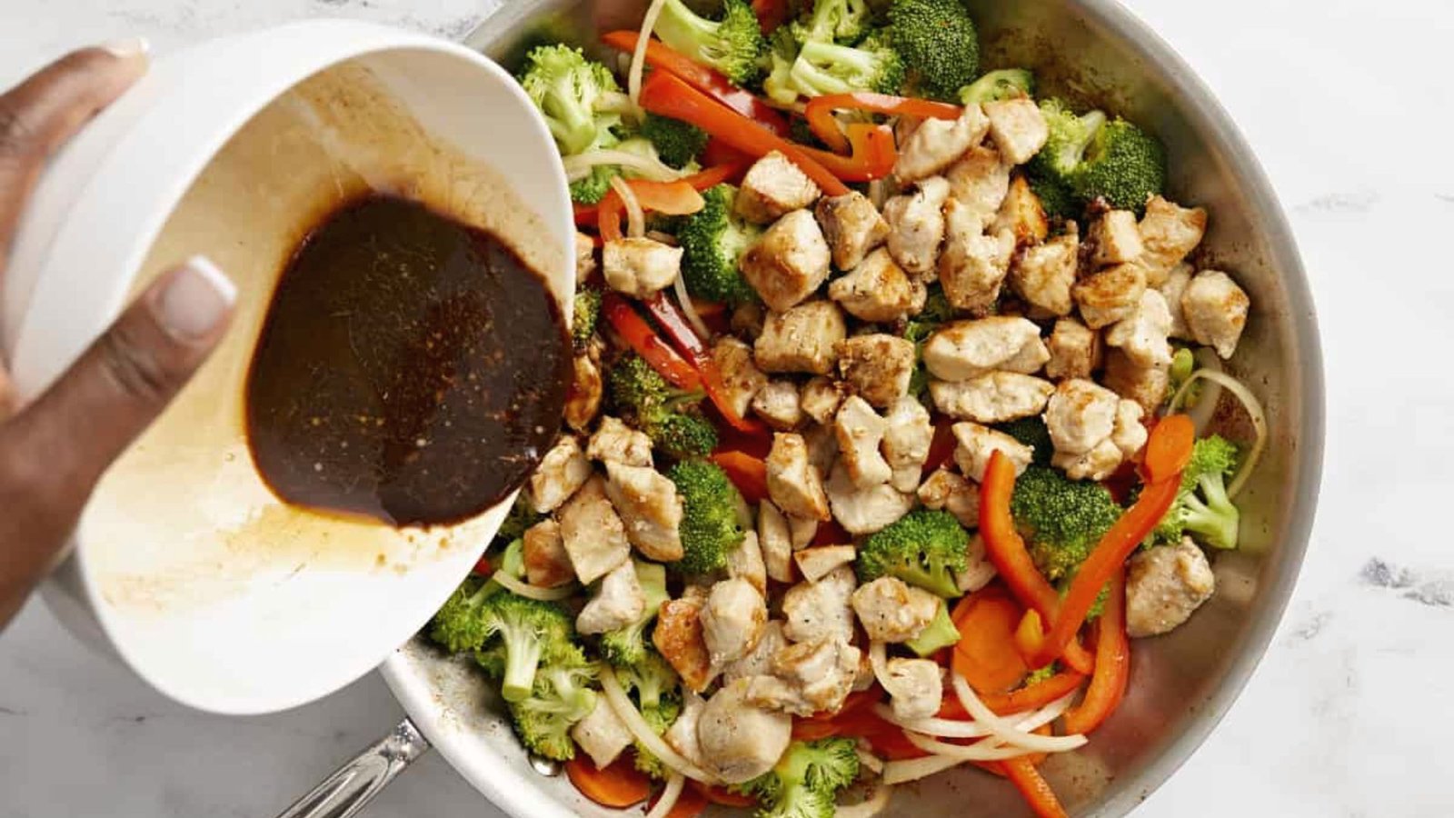 A person drizzling sauce onto a pan of chicken and vegetables, and Mix Everything Together.