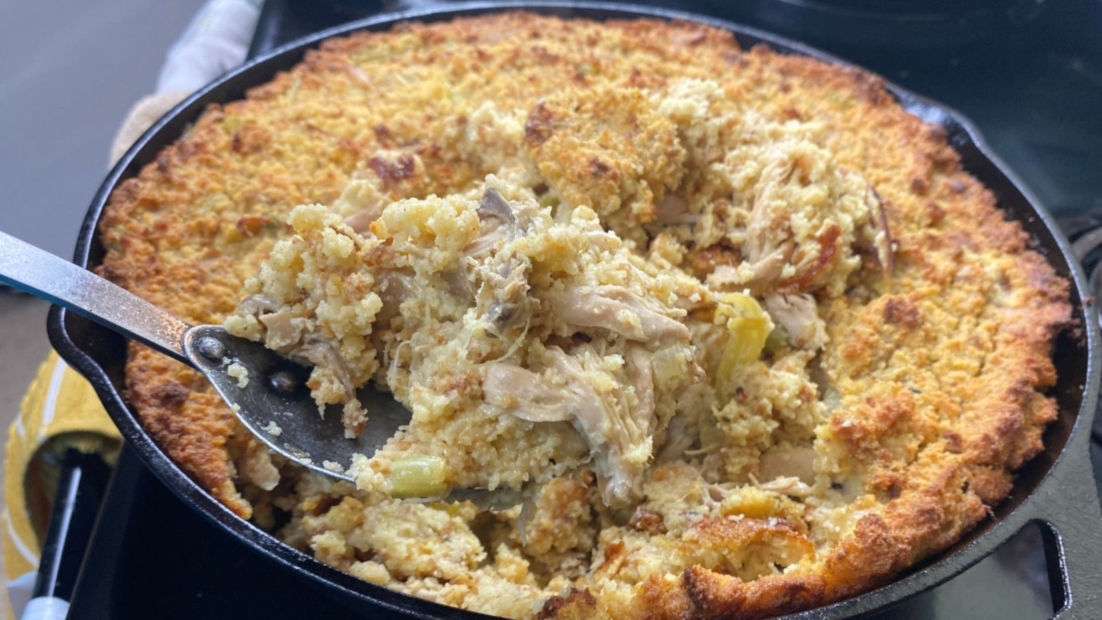 A skillet filled with a golden-brown chicken dressing casserole, ready to be served.
