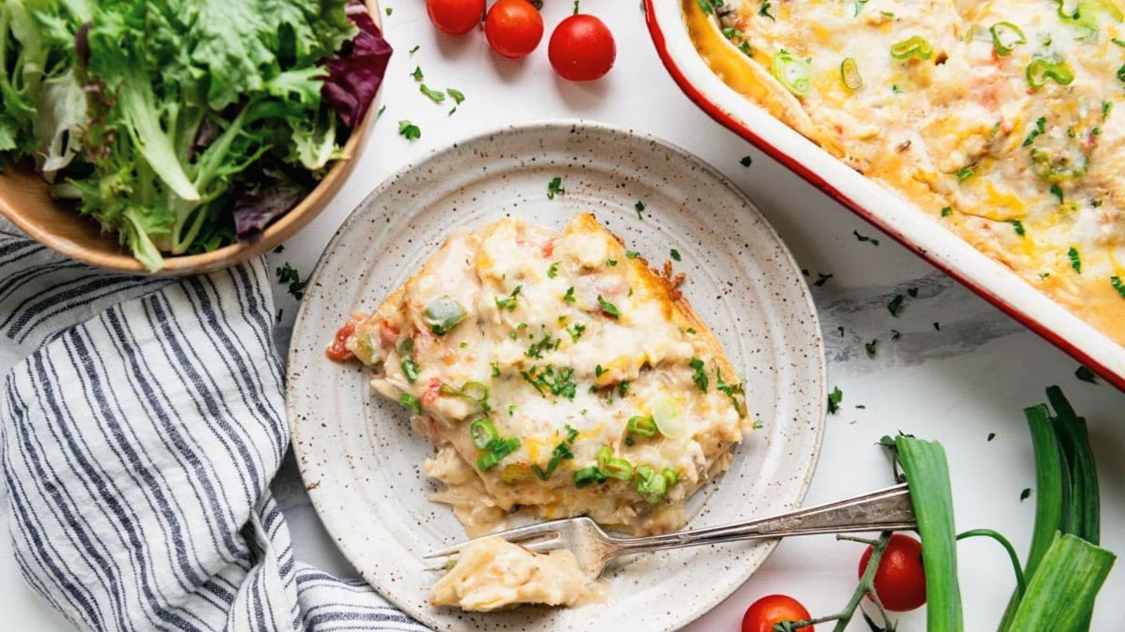 A delicious chicken enchilada casserole topped with cheese, served in a baking dish with storage and freezing tips nearby.