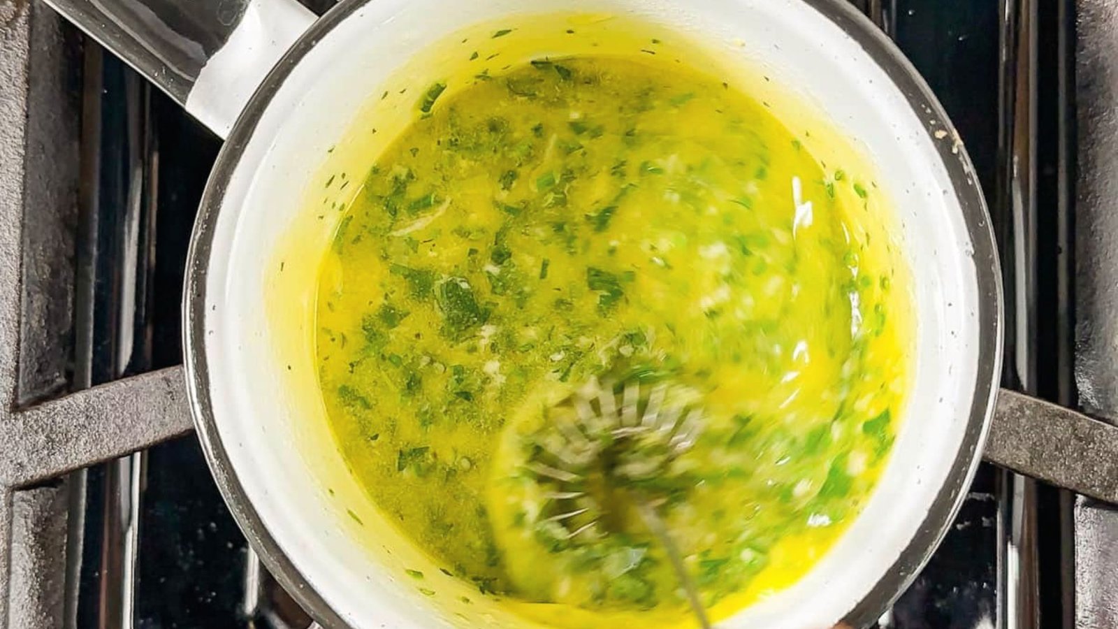 A pot is being stirred on a stove, indicating the preparation of a garlic butter base.