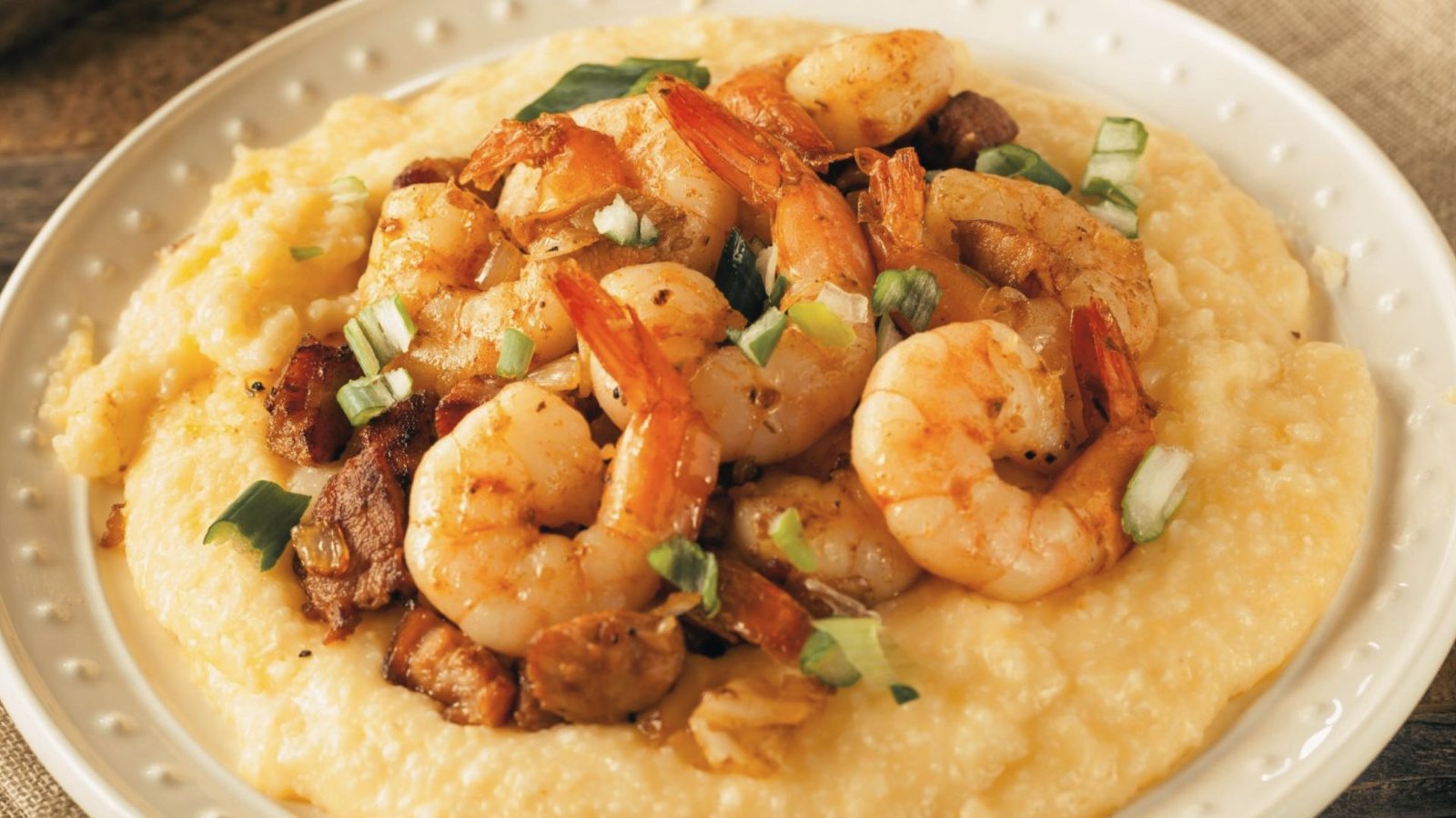 A white plate featuring a serving of shrimp and grits, showcasing the dish's creamy texture and vibrant shrimp.