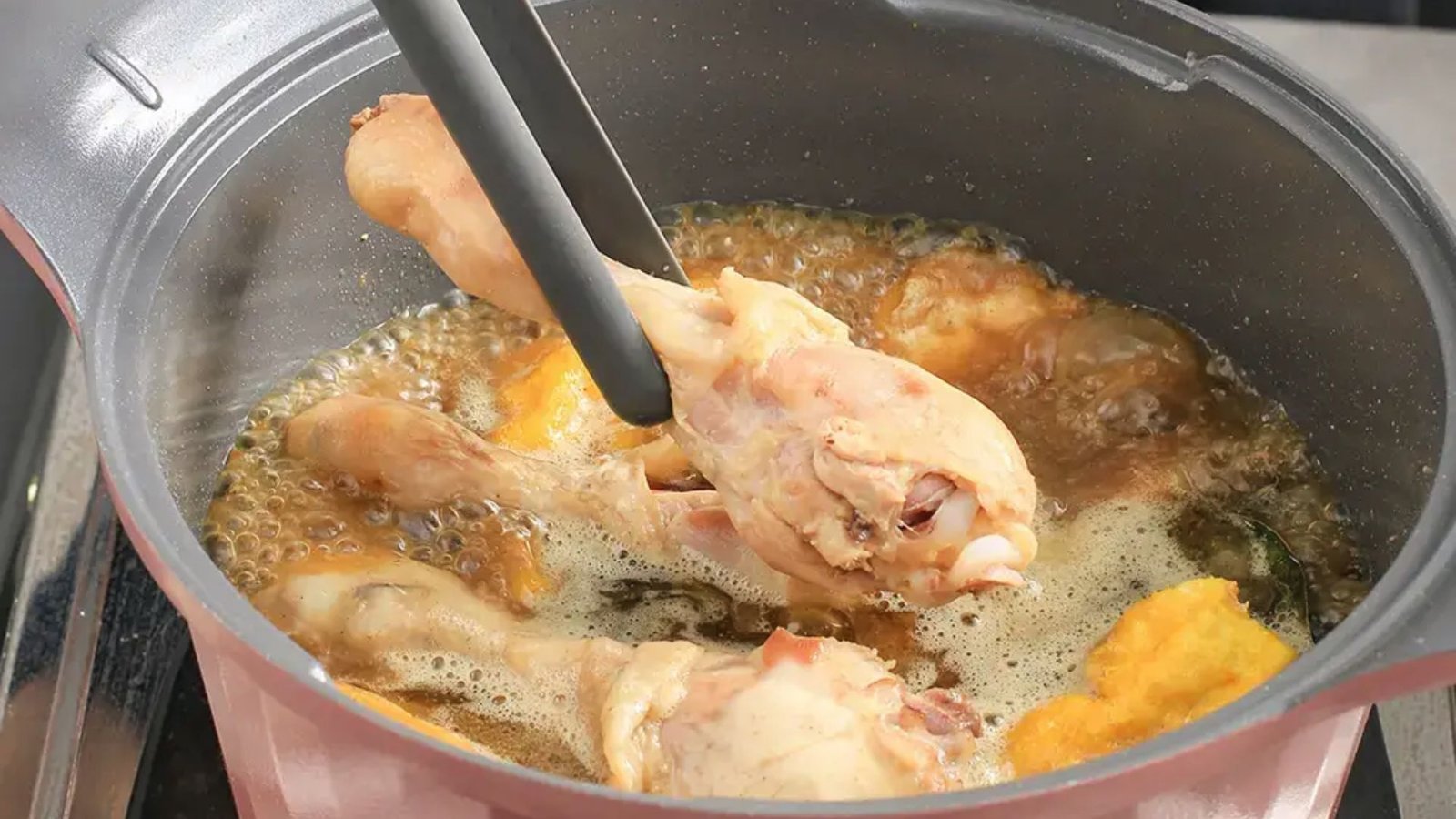 A skillet filled with chicken wings sizzling, illustrating the preparation of a delicious chicken wing boil dish.