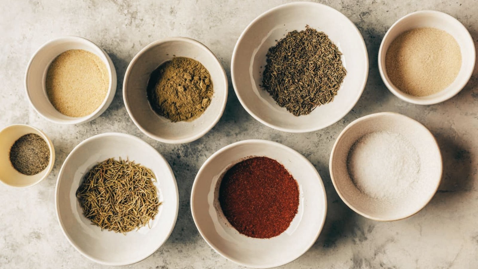 A variety of spices in bowls, essential ingredients for a turkey rub recipe.