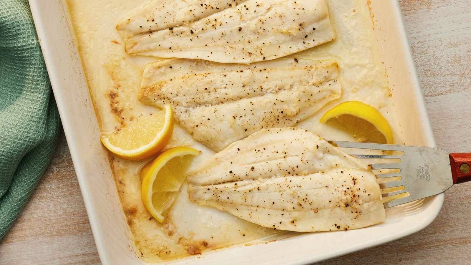 A pan with swai fish fillets topped with fresh lemon slices, ready for an easy oven-baked recipe.