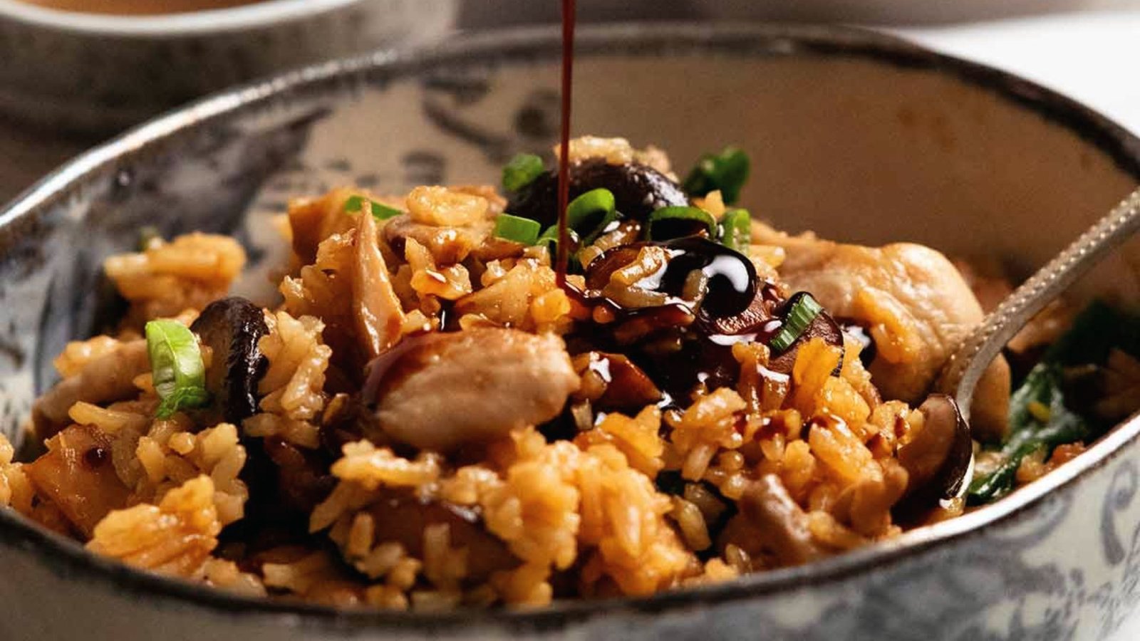A serving of rice with tender chicken and pouring sauce in the meal, ideal for flavorful rice cooker chicken dishes.
