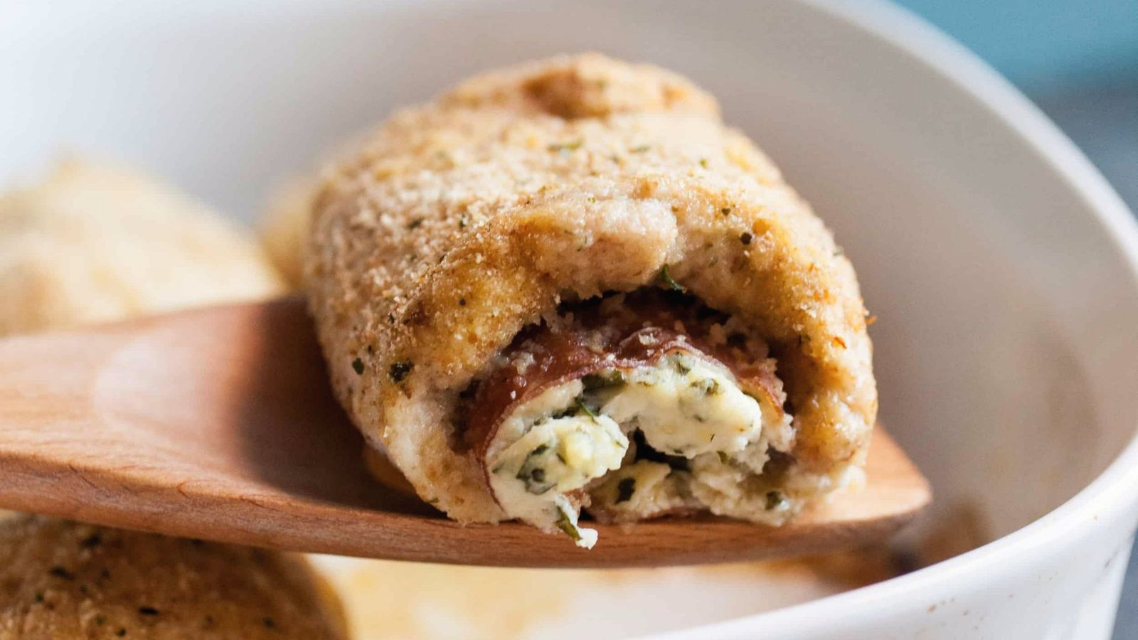 Close-up of a golden-brown chicken rollatini, showcasing its cheesy and savory filling.