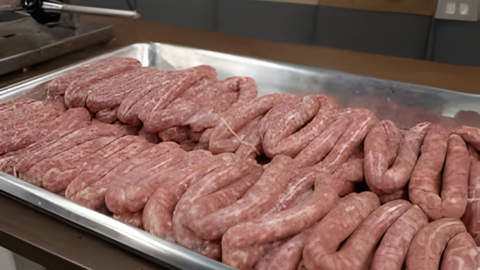 A counter displaying a tray of raw sausages, highlighting the importance of resting for better texture.
