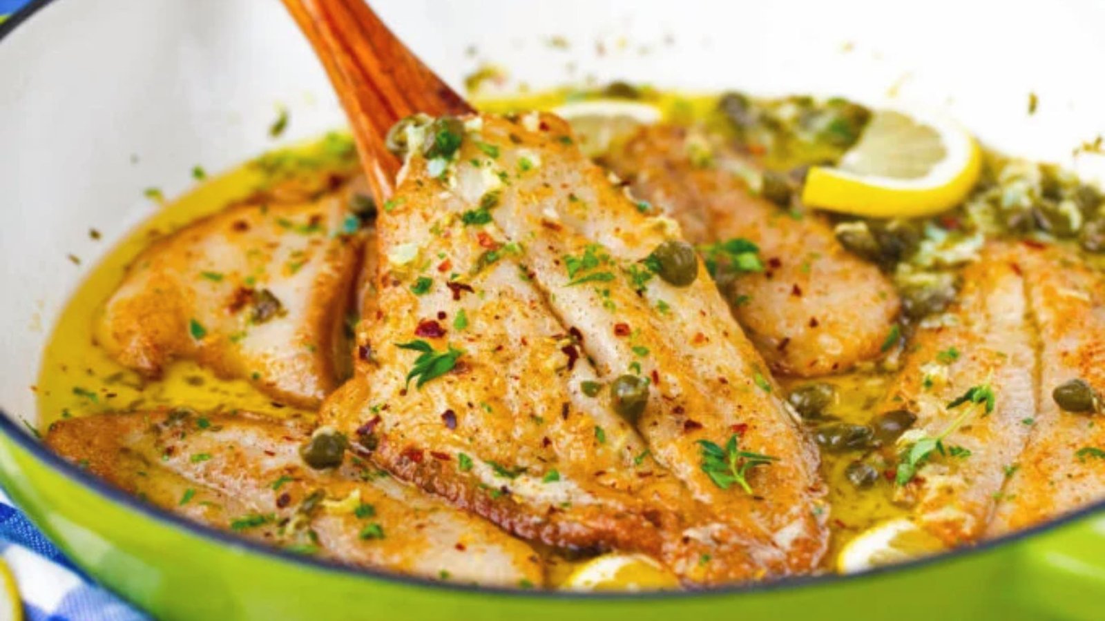 A skillet containing swai fish garnished with lemon slices, highlighting a delicious recipe enhancement.