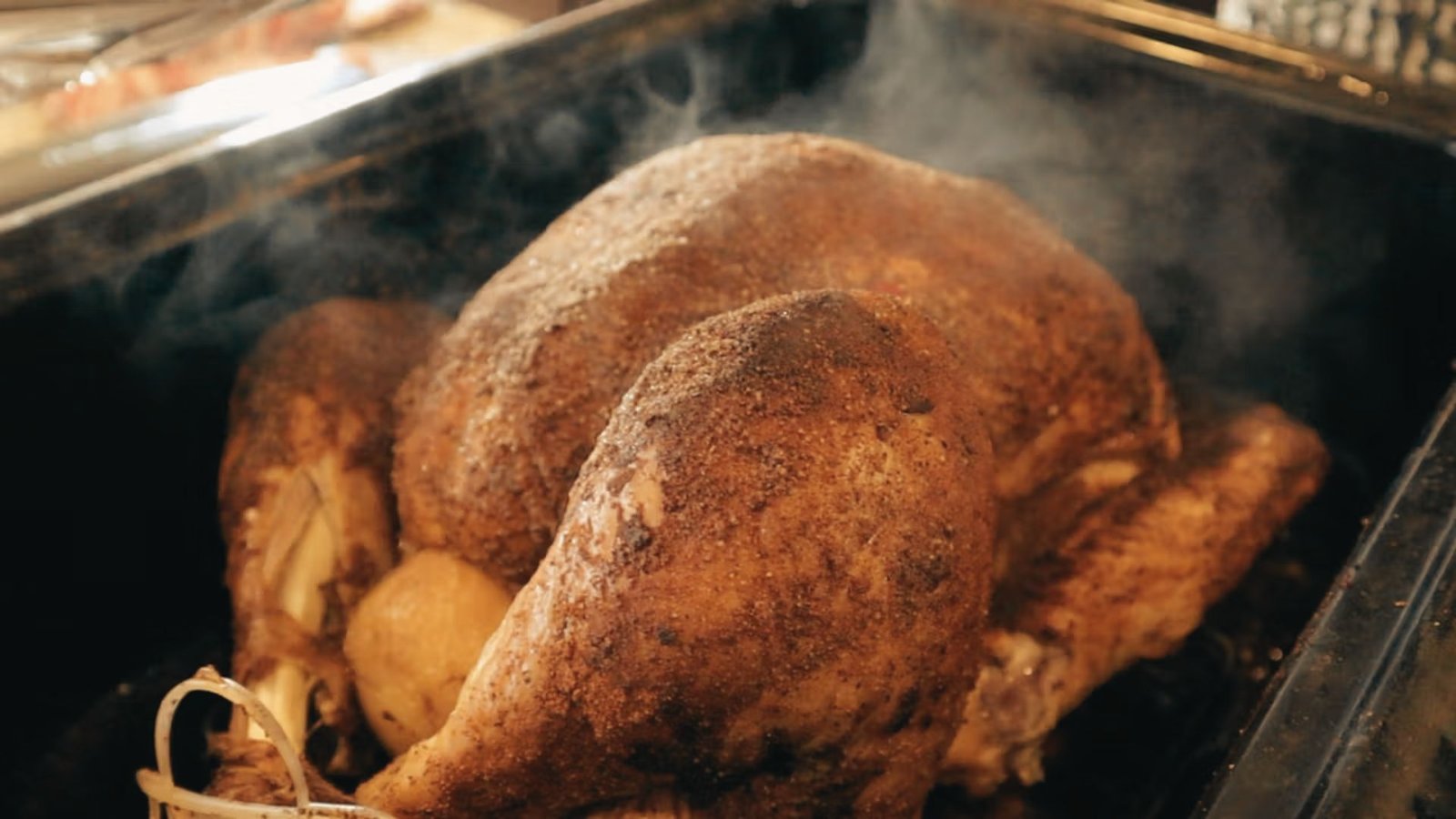 A large turkey is cooked in a pan, seasoned with a homemade smoked turkey rub recipe.