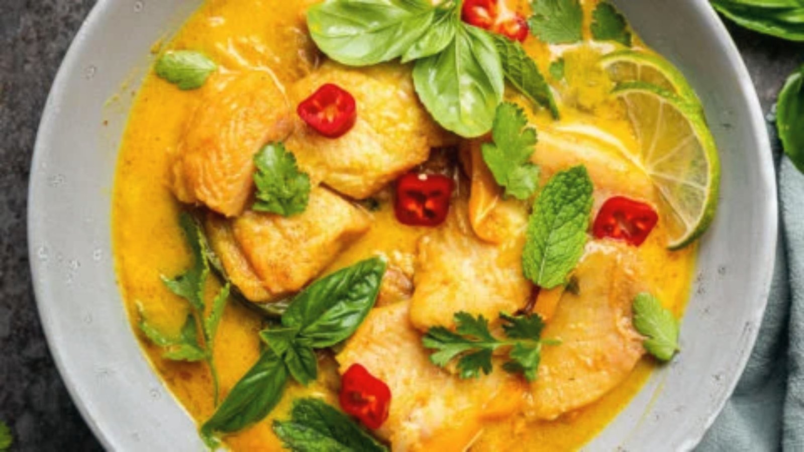 A bowl of thai fish curry garnished with lime leaves, ready to be served.