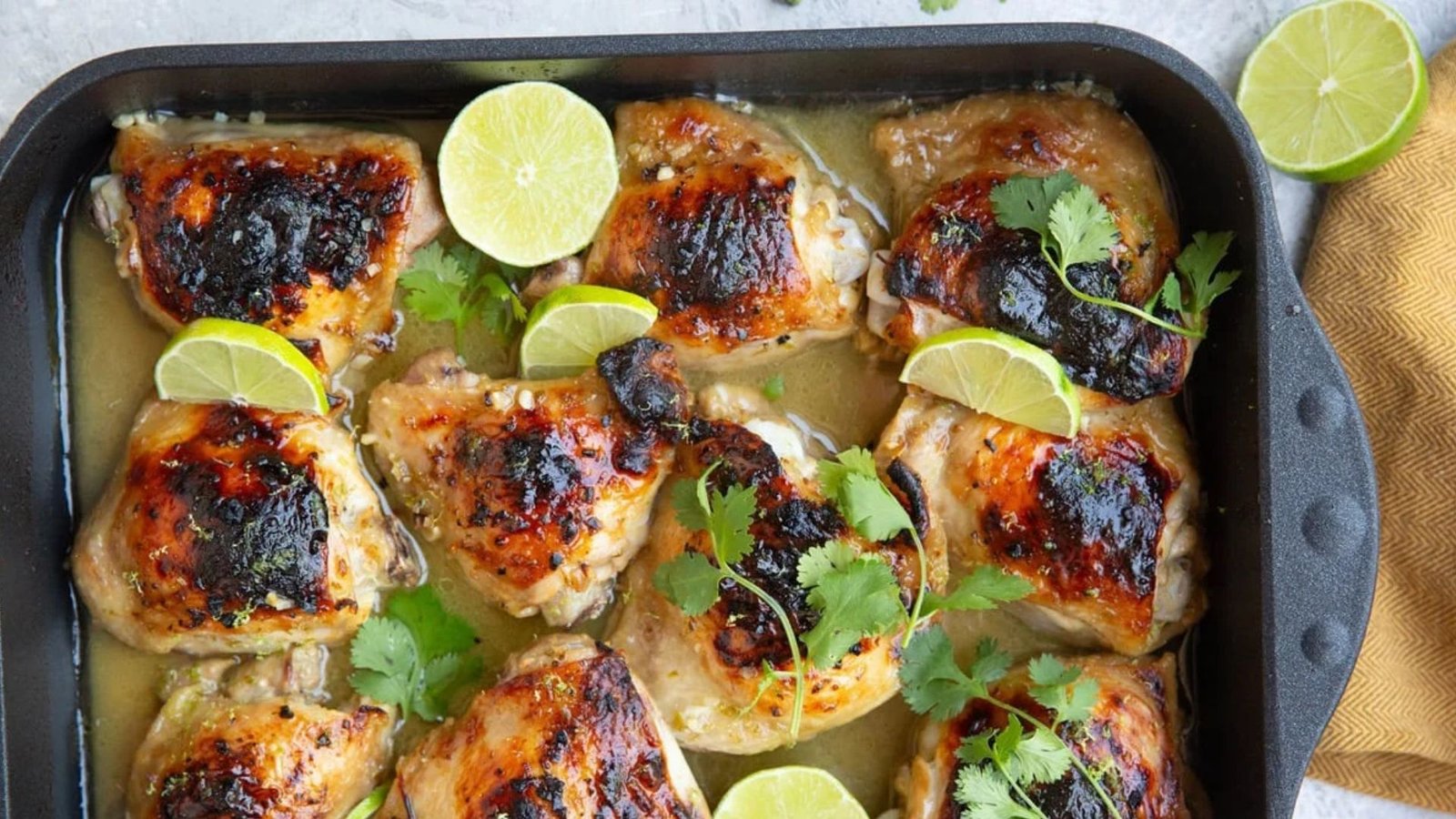 Juicy chicken thighs with lime and cilantro arranged in a baking dish, showcasing a vibrant and flavorful dish.