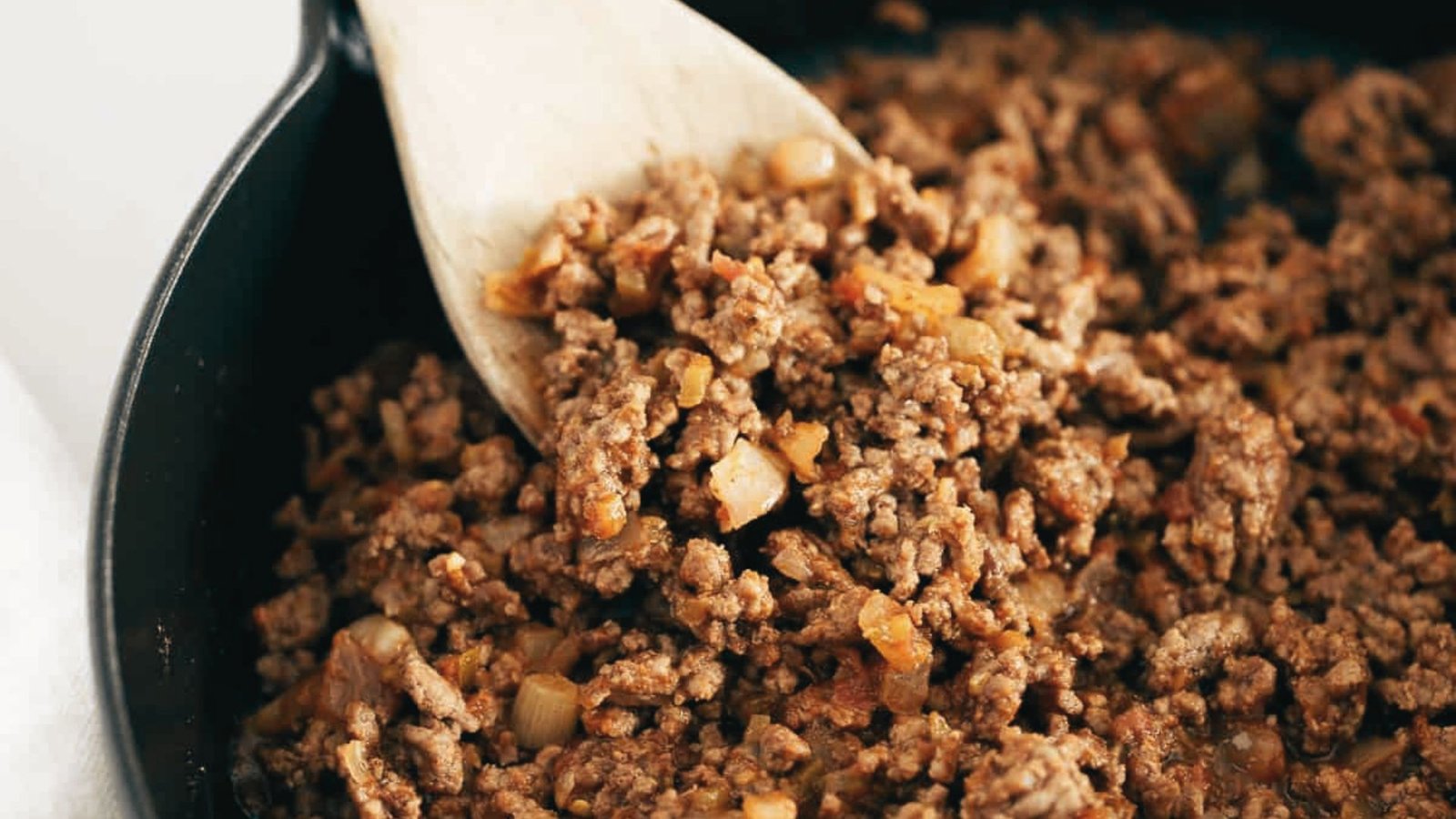 A skillet with ground beef and a wooden spoon, showcasing a meal prep option for making extra taco meat.