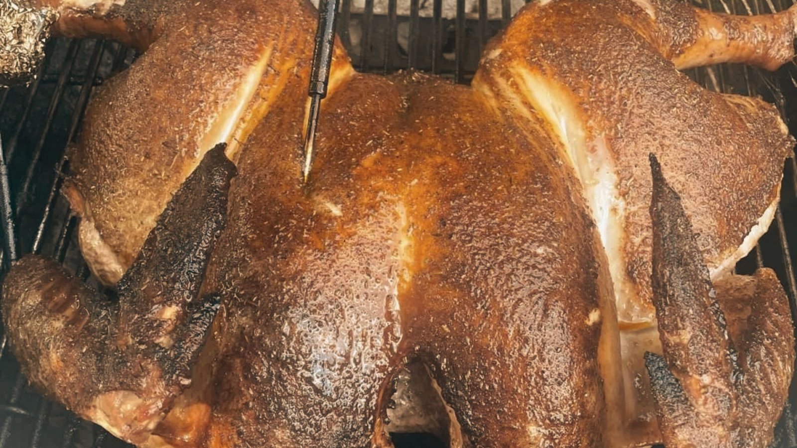 A large roast chicken sizzling on a grill, showcasing the Best Smoked Turkey Rub Recipe for an extra smoky flavor.