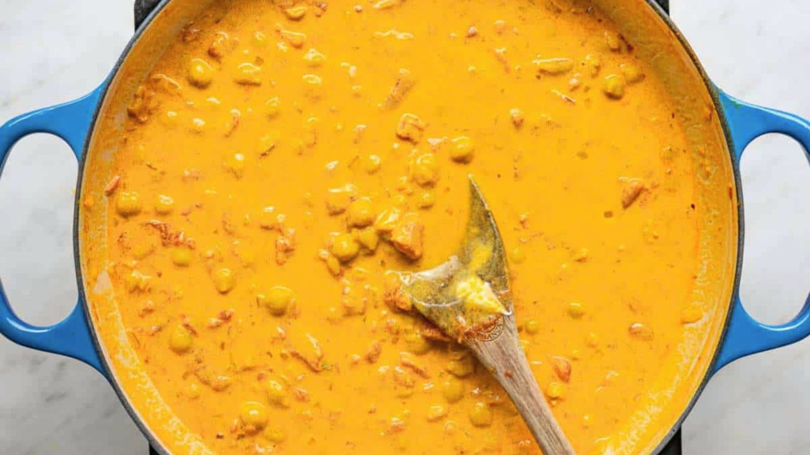 Curry simmering in a blue pot, showcasing a rich coconut curry sauce.