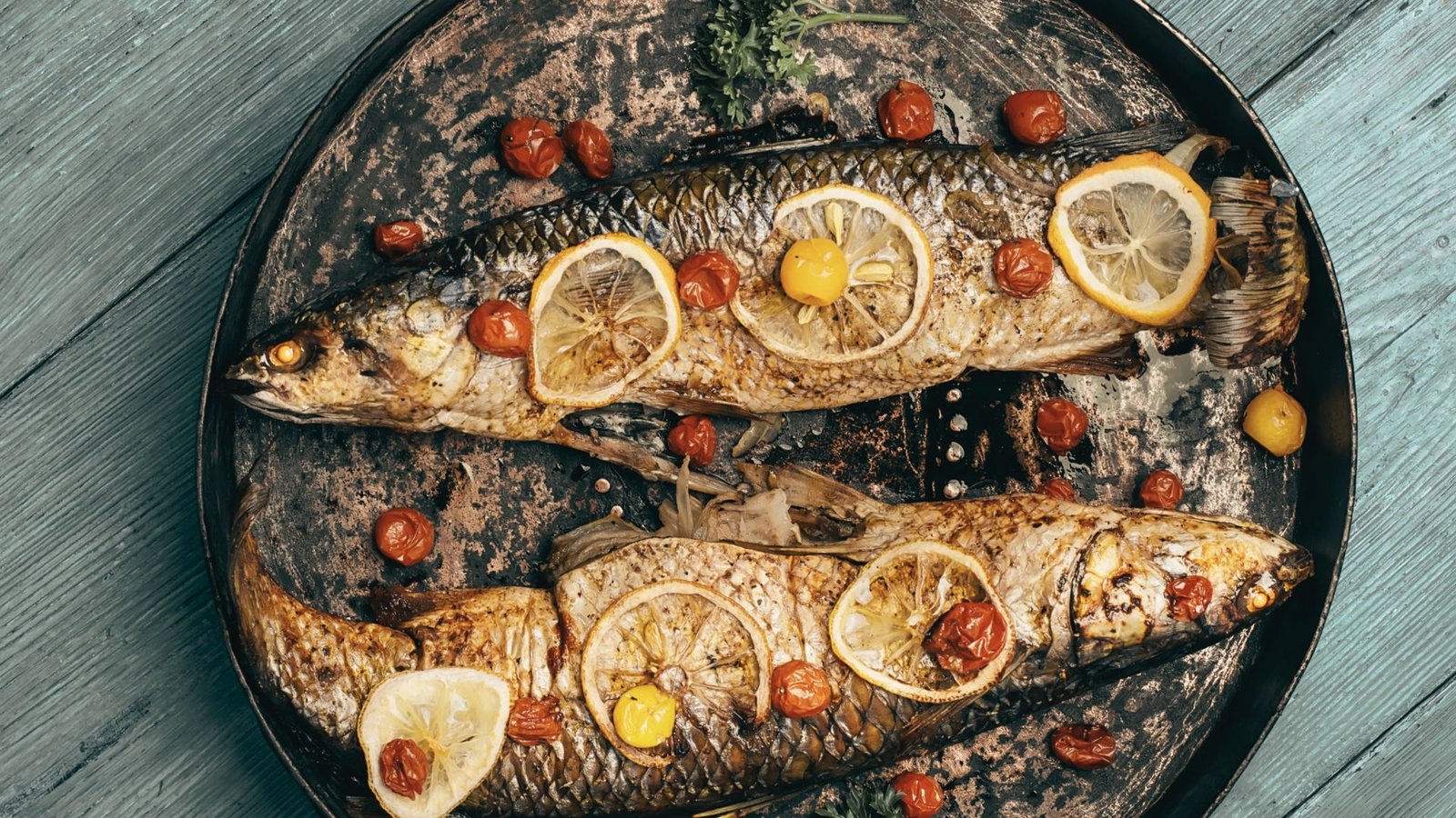 Grilled fish with lemon slices displayed on a wooden table, showcasing a delicious autumn seafood dish.