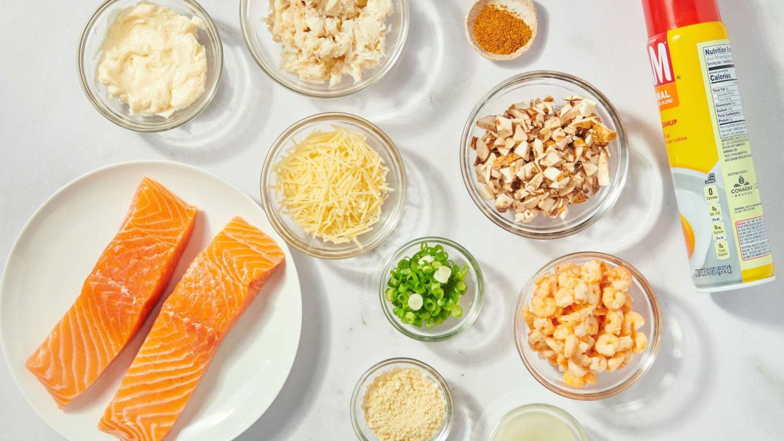 Ingredients for stuffed salmon with crabmeat and shrimp displayed on a white table.