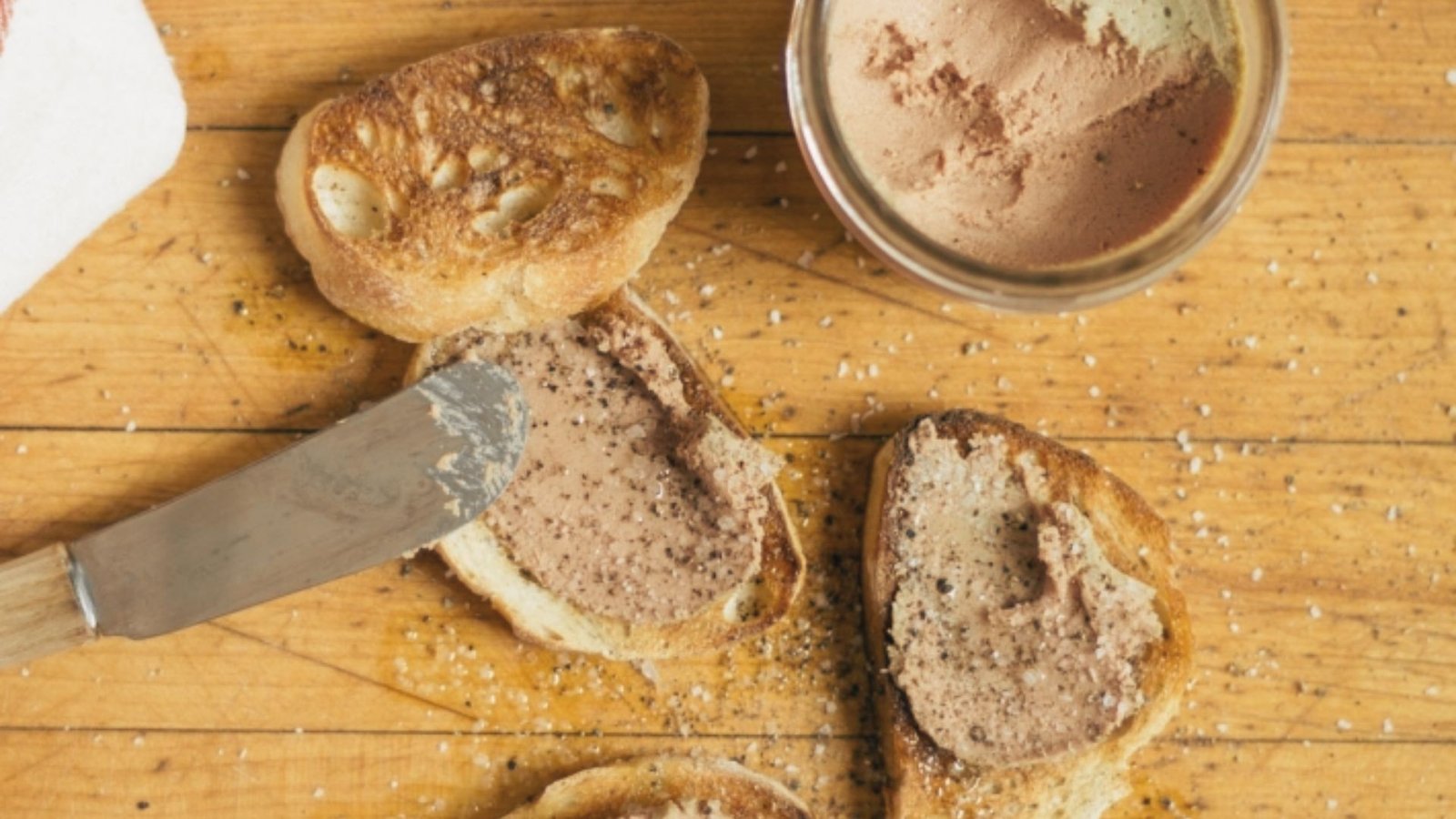 A table displays a knife, a loaf of bread, and a jar of butter, indicating ingredients for a Chicken Liver Mousse recipe.