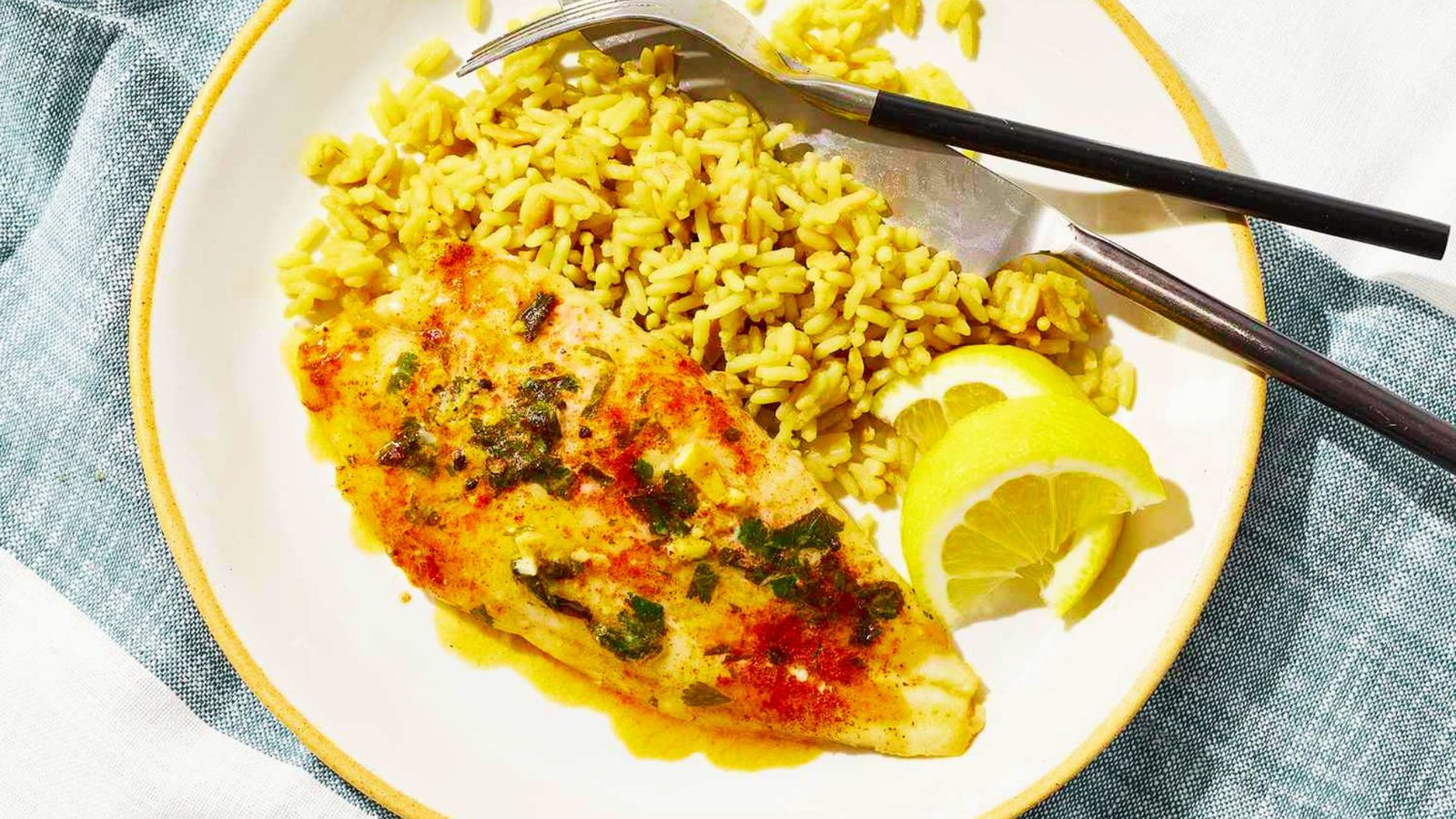 A plate featuring rice, Swai fish, and fresh lemon wedges, highlighting a beginner-friendly fish cooking recipe.