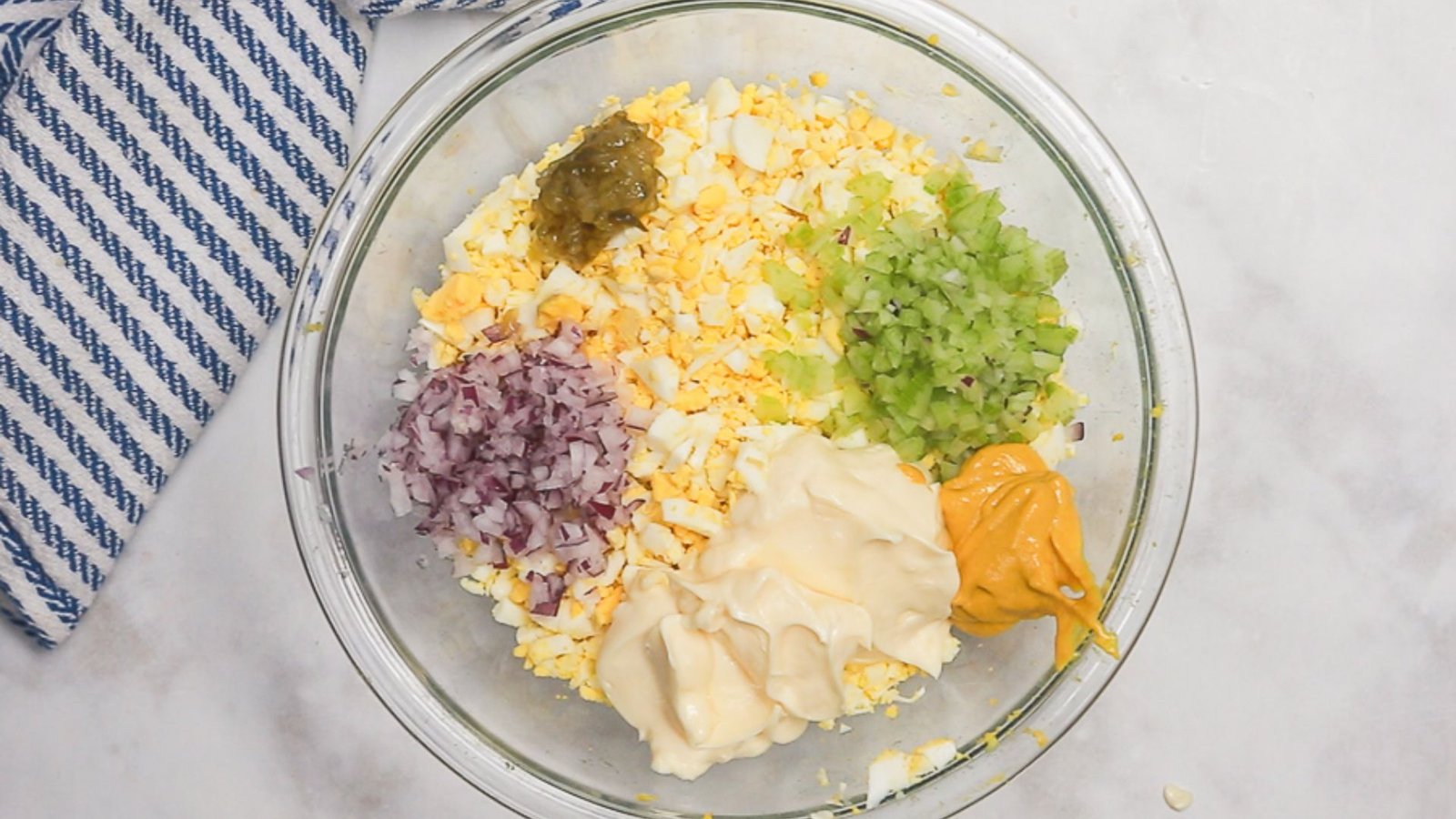 A bowl filled with cheese, onions, and various ingredients for making dressing.