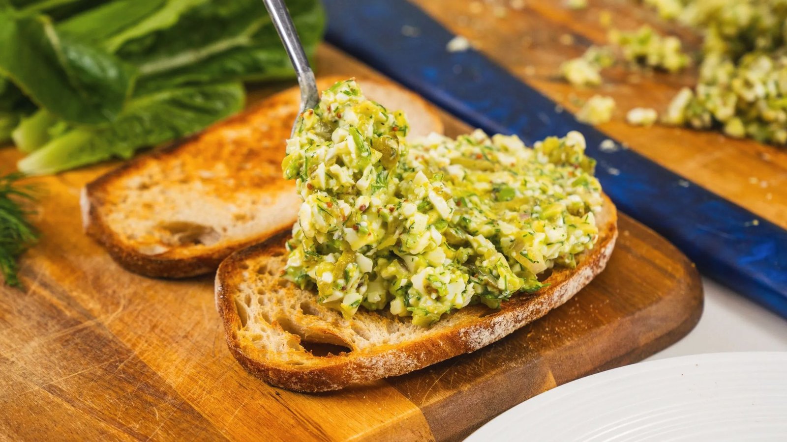 A sandwich topped with delicious egg salad with pickles variation.