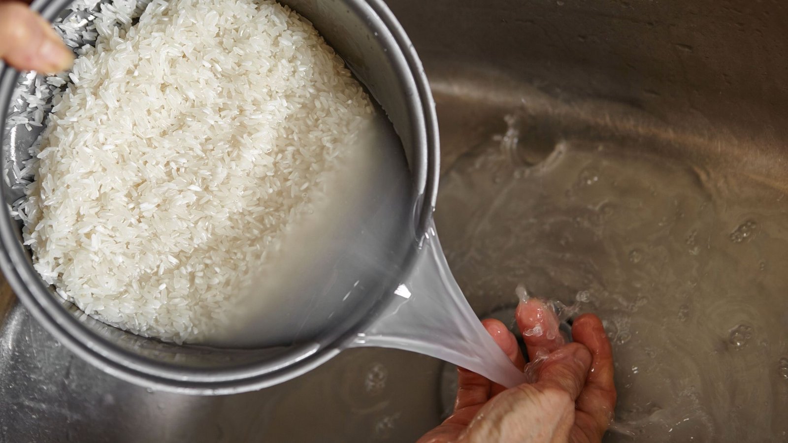 A person is washing rice that is in a bowl and initiating flavoring the rice for cooking.