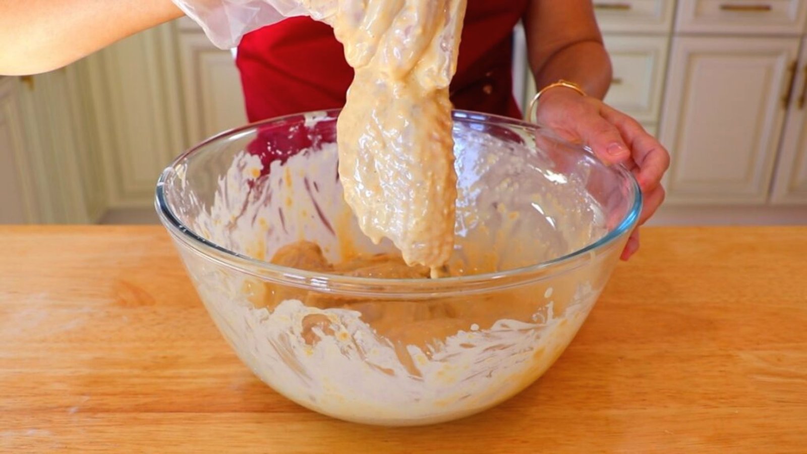 A person mixing batter in a bowl, preparing to season and coat chicken wings for cooking.