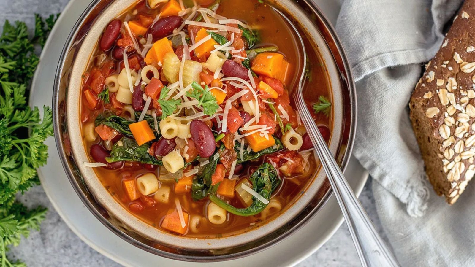 A delicious bowl of Minestrone Soup and, filled with assorted vegetables, meat and pasta in a flavorful broth.