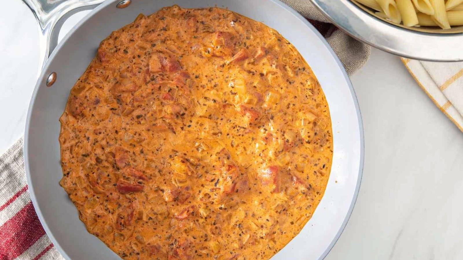 A pan filled with creamy Tex-Mex sauce mixed with pasta, showcasing a rich and flavorful dish ready to serve.