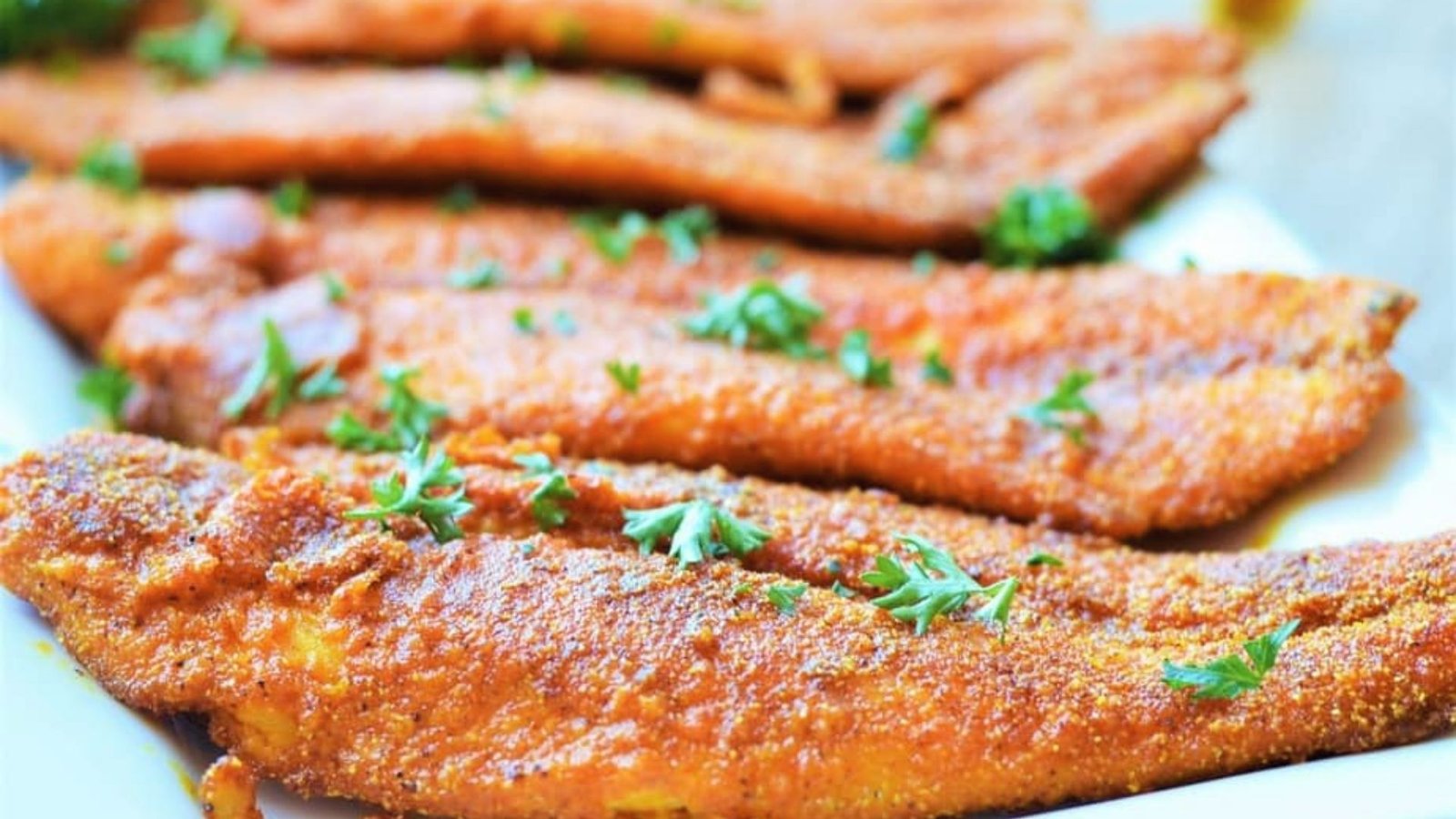 A plate of crispy fried fish, elegantly presented with a sprig of parsley, perfect for swai fish recipe enthusiasts.
