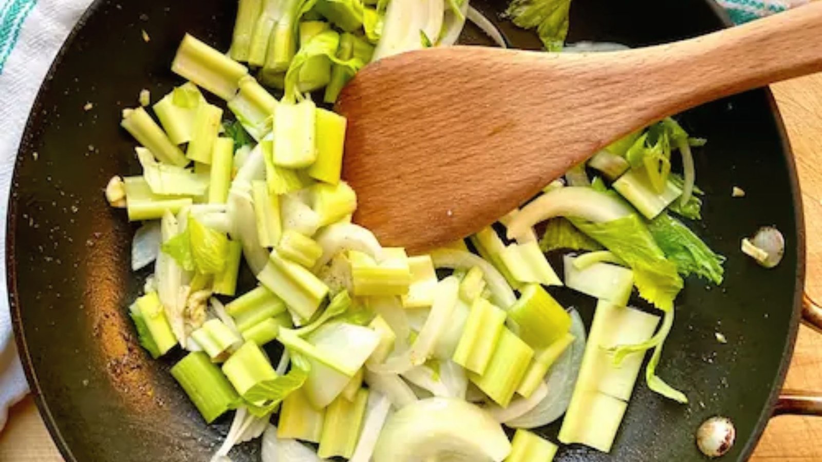A pan filled with chopped celery and onions, ready for sautéing in a cooking process.