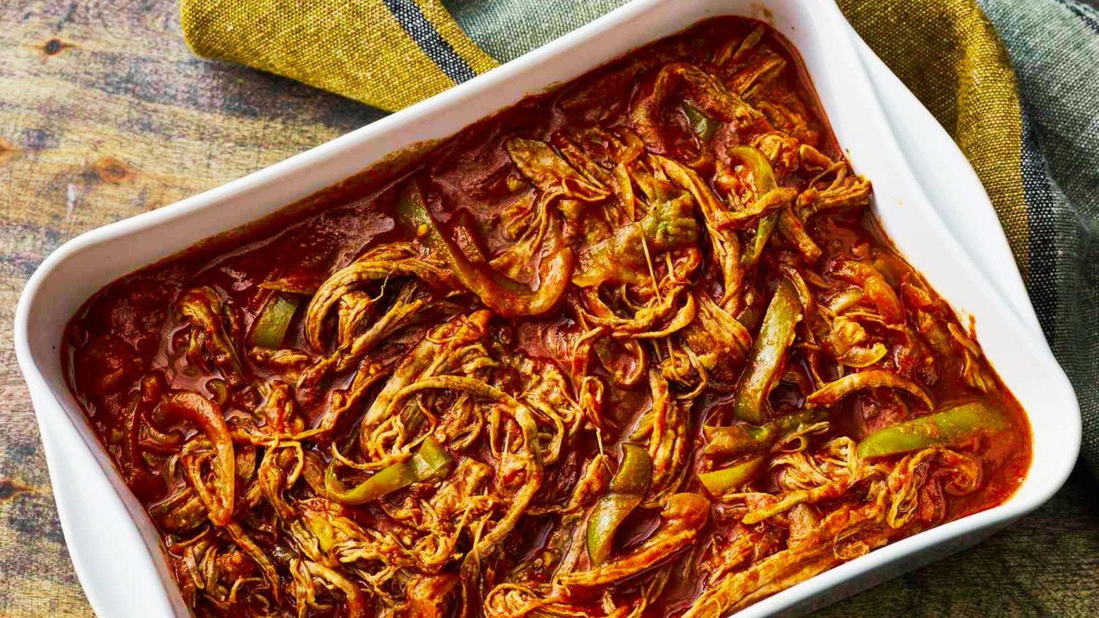 A dish of shredded chicken, prepared for an authentic Cuban Ropa Vieja recipe, emphasizing its flavorful ingredients.