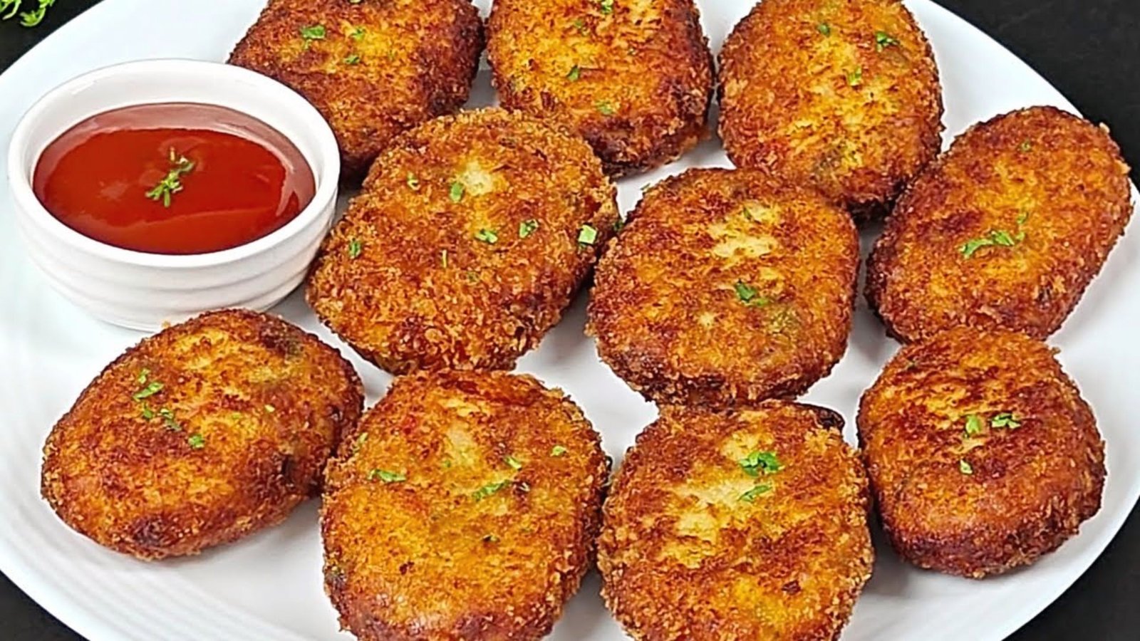 A plate of golden fried chicken cutlets accompanied by a small bowl of ketchup.