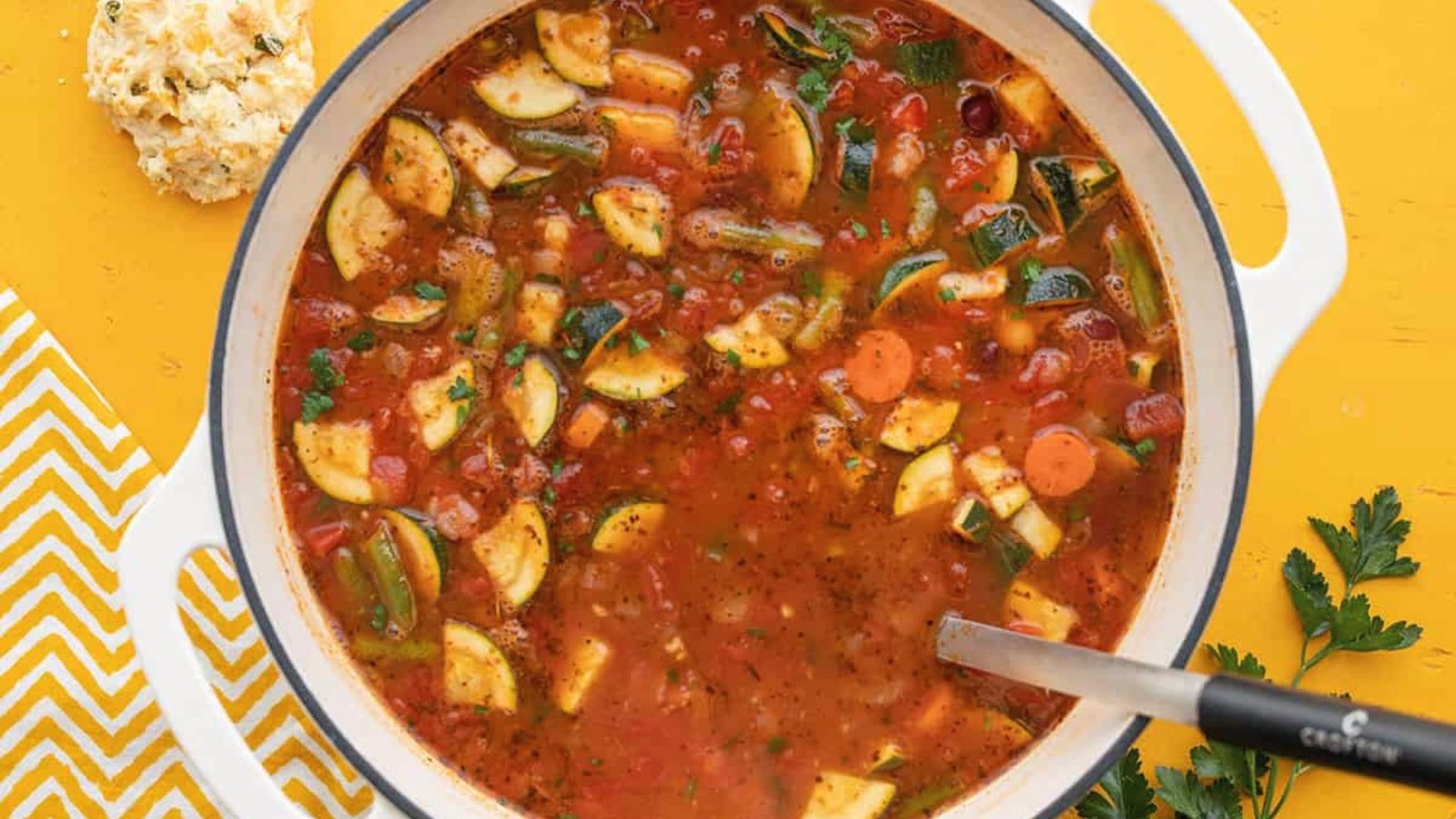 A steaming pot of minestrone soup accompanied by a spoon, showcasing a delicious meal option.