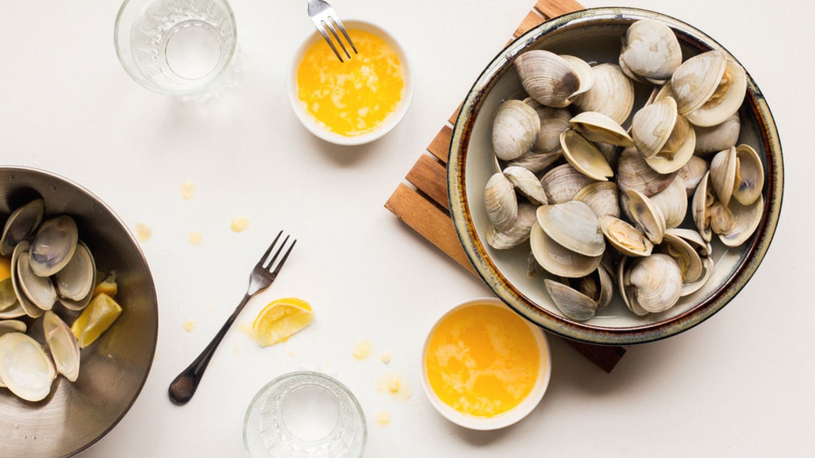A bowl of clams with lemon juice and a knife, showcasing ingredients for a delicious Little Neck Clams recipe.