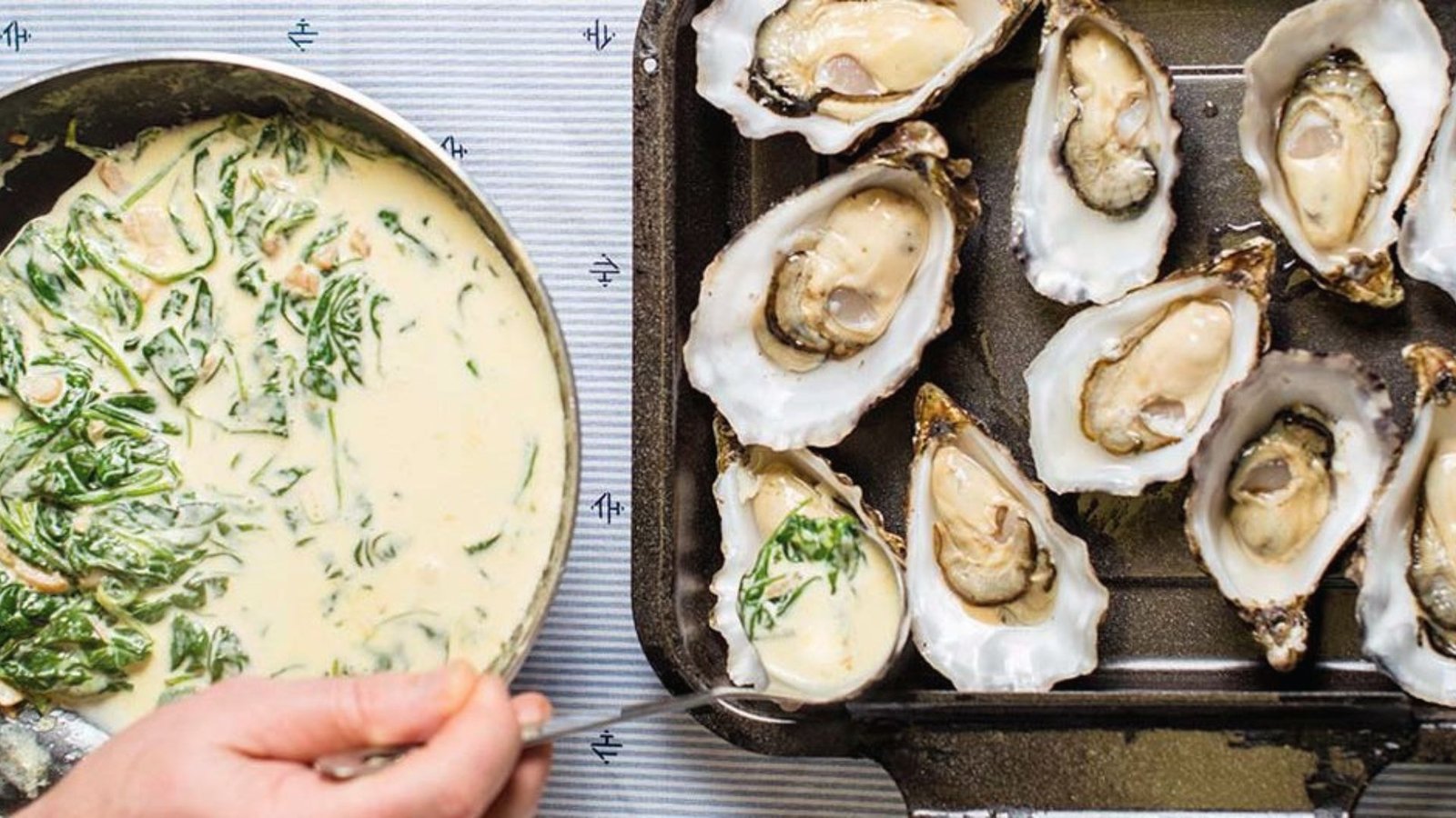 A pan filled with oysters topped with fresh spinach, ready for assembly in the cooking process.