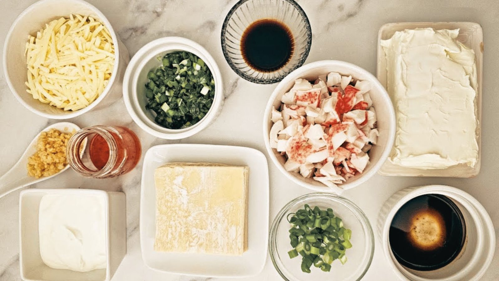 A collection of ingredients for crab and shrimp salad, featuring crab, shrimp, herbs, and spices arranged on a table.