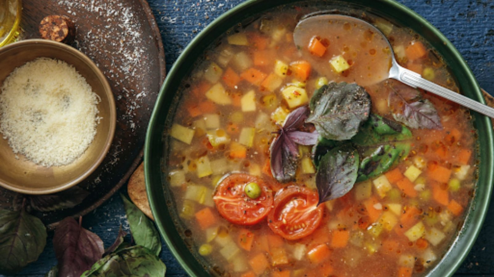 A bowl of hearty Minestrone vegetable soup with meat and a spoon next to it.