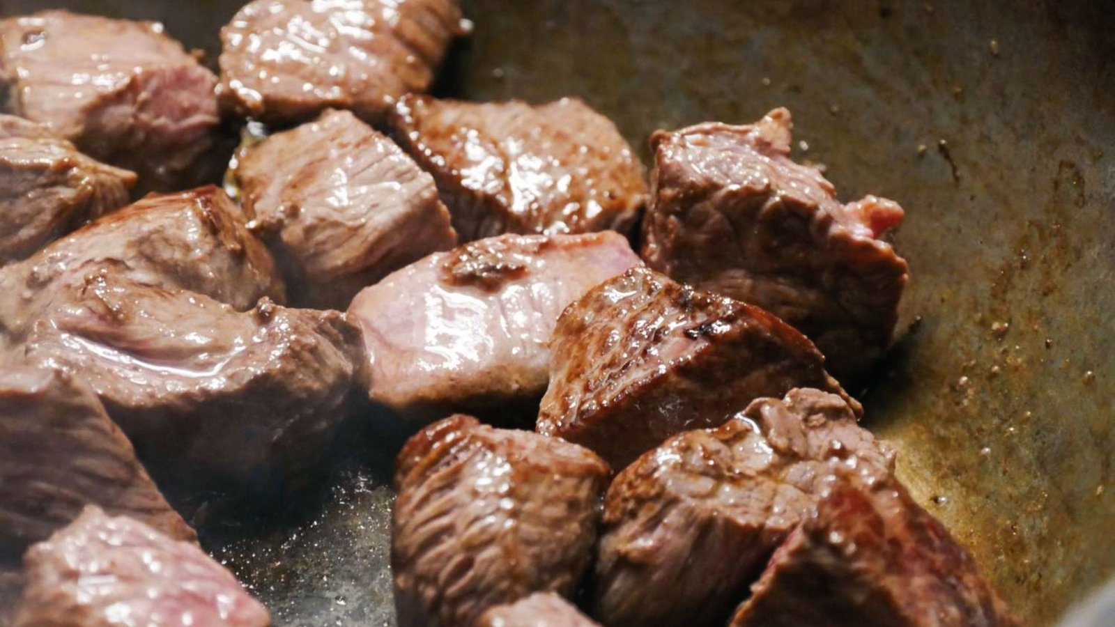 A sizzling steak in a pan on the stove, demonstrating the initial step of browning for improvised flavor.