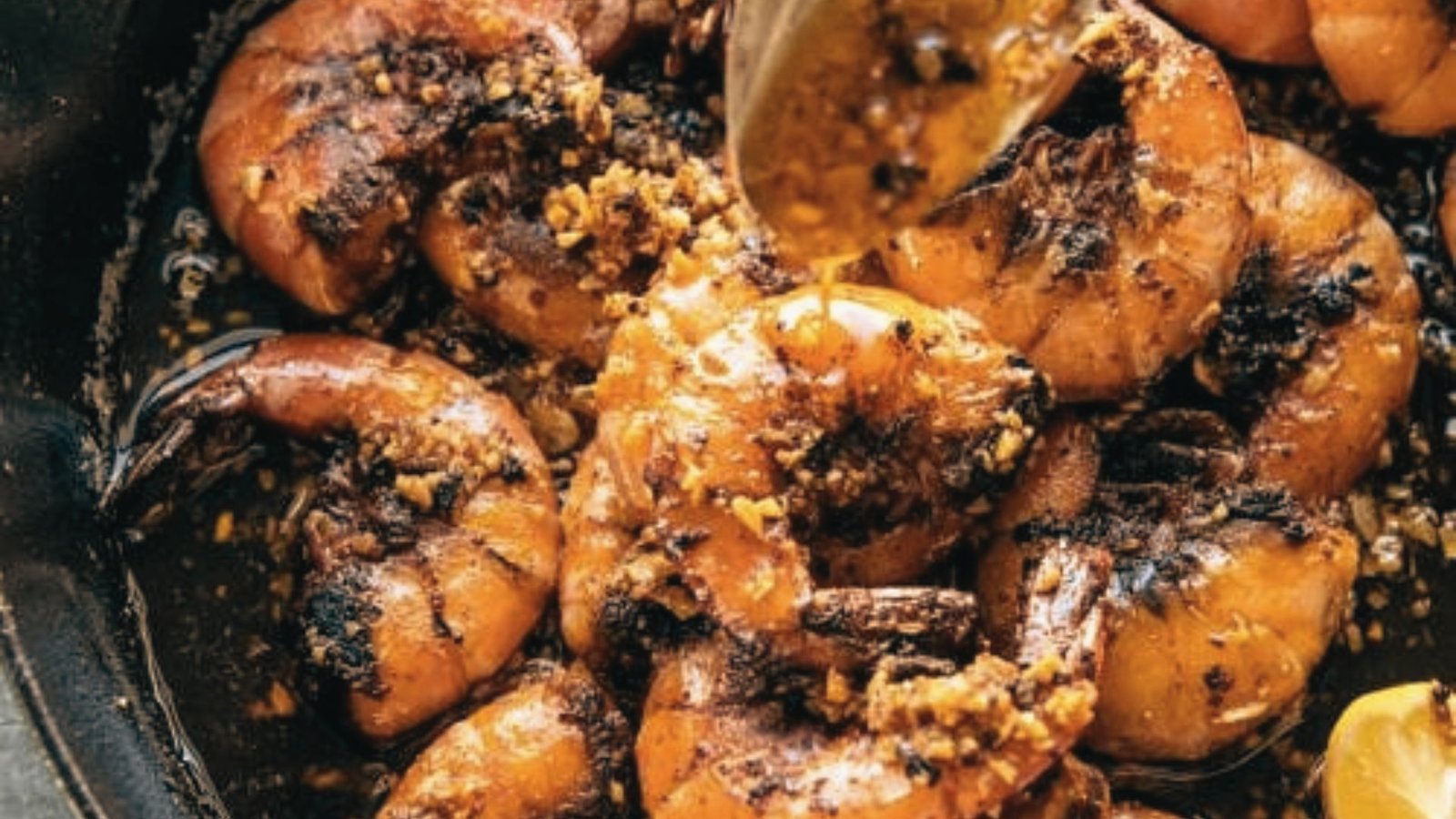 A pan filled with pink, juicy shrimp and fresh lemon wedges, ready for peeling and eating.