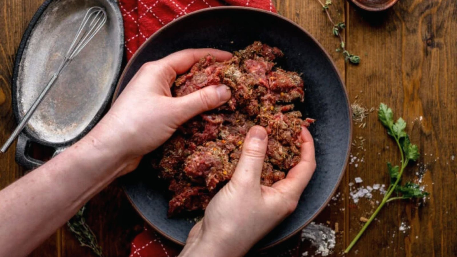 A person with a bowl filled with raw meat, ready for mixing with seasonings in the cooking process.