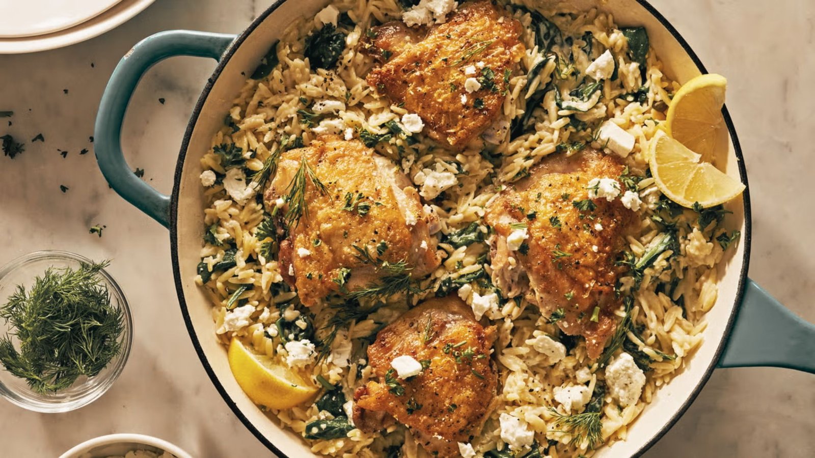 A skillet filled with lemon chicken, orzo pasta, spinach, and rice, showcasing a creamy one-pot meal.
