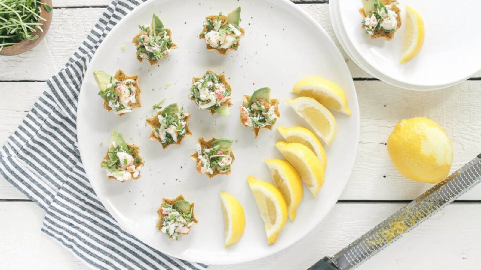 A plate of assorted appetizers of lobster bites, garnished with fresh lemon wedges.