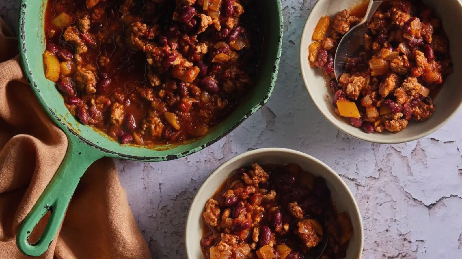 Three bowls of thick, flavorful chili with meat and beans, simmered to perfection.