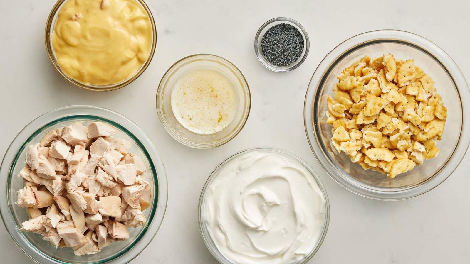 Ingredients for a chicken and rice casserole, including chicken, rice, poppy seeds, and various seasonings.